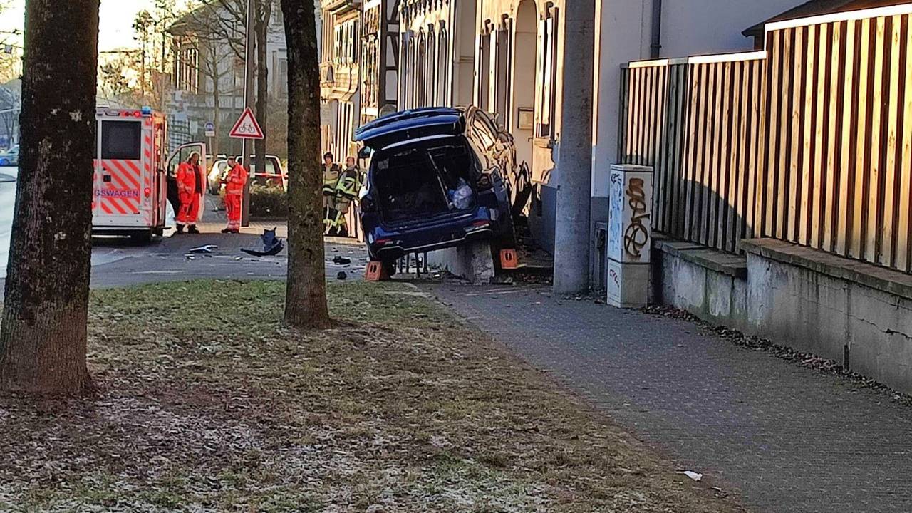 Auto steht nach einem Unfall an einer Hauswand. Im Hintergrund ist ein Krankenwagen samt Besatzung zu sehen.