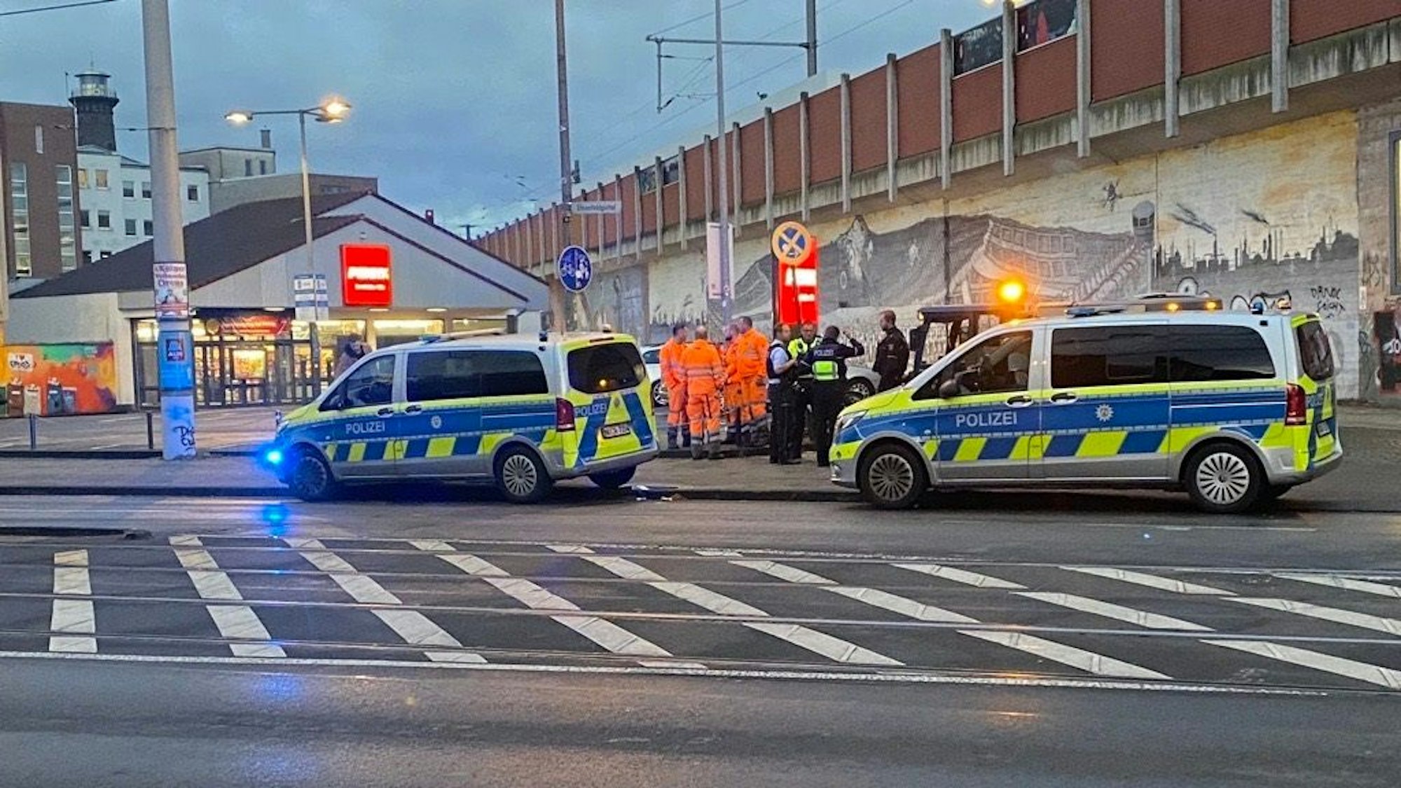 Zwei Streifenwagen parken an der Straße, auf dem Bürgersteig stehen mehrere Polizeikräfte sowie Mitarbeitende der AWB.