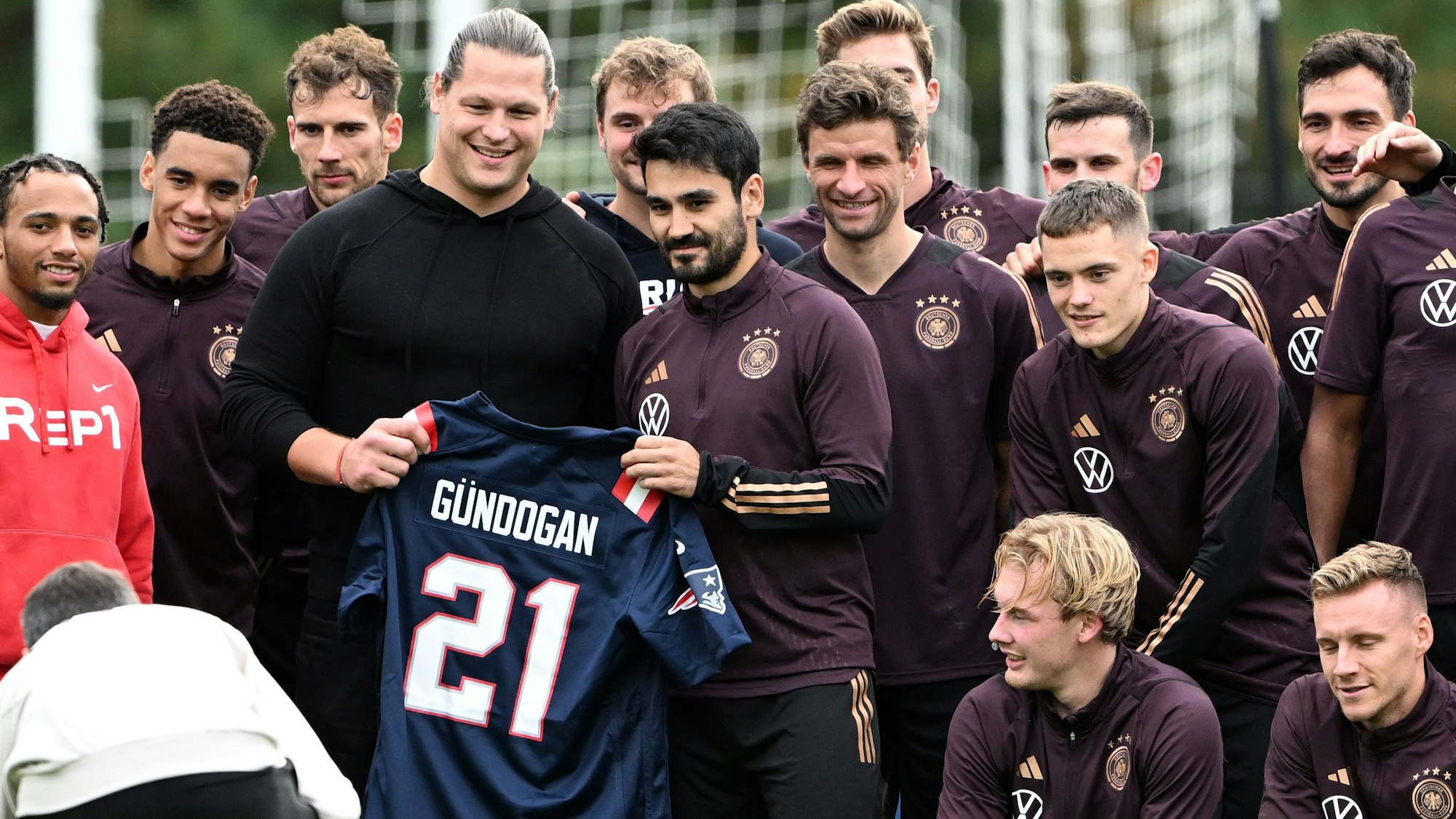 Der ehemalige NFL-Profi Markus Kuhn (l) präsetiert während des Trainings ein NFL-Trikot mit dem Namen von Deutschlands Kapitän Ilkay Gündogan.