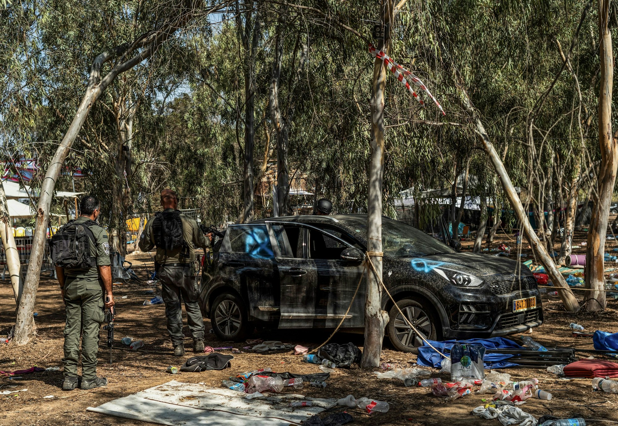 Israelische Soldaten stehen neben einem verlassenen Auto auf dem Gelände des Supernova-Wüstenmusikfestivals, nachdem es den israelischen Streitkräften gelungen ist, die Gegend um Re'im zu sichern.