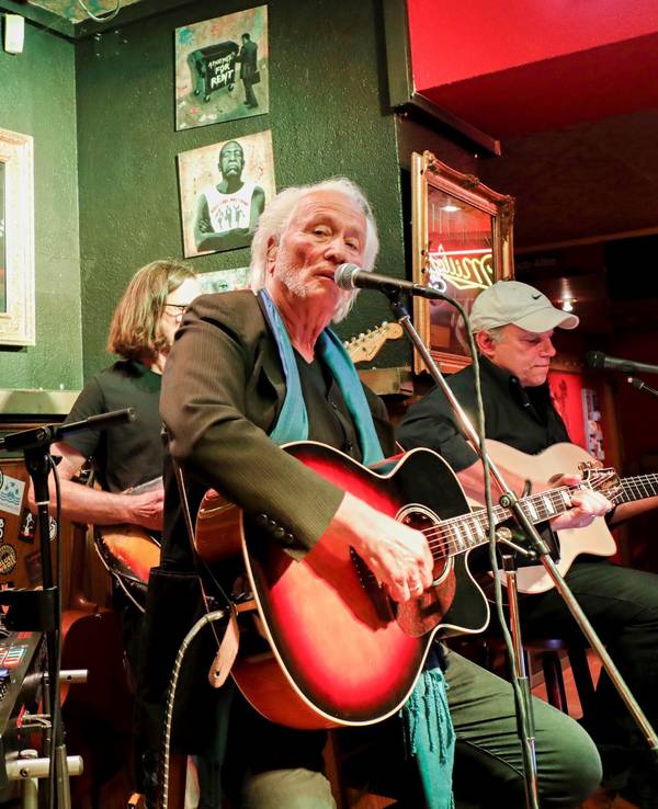 Vier Musiker mit Gitarren und Keyboard auf einer kleinen Bühne in einer Bar.