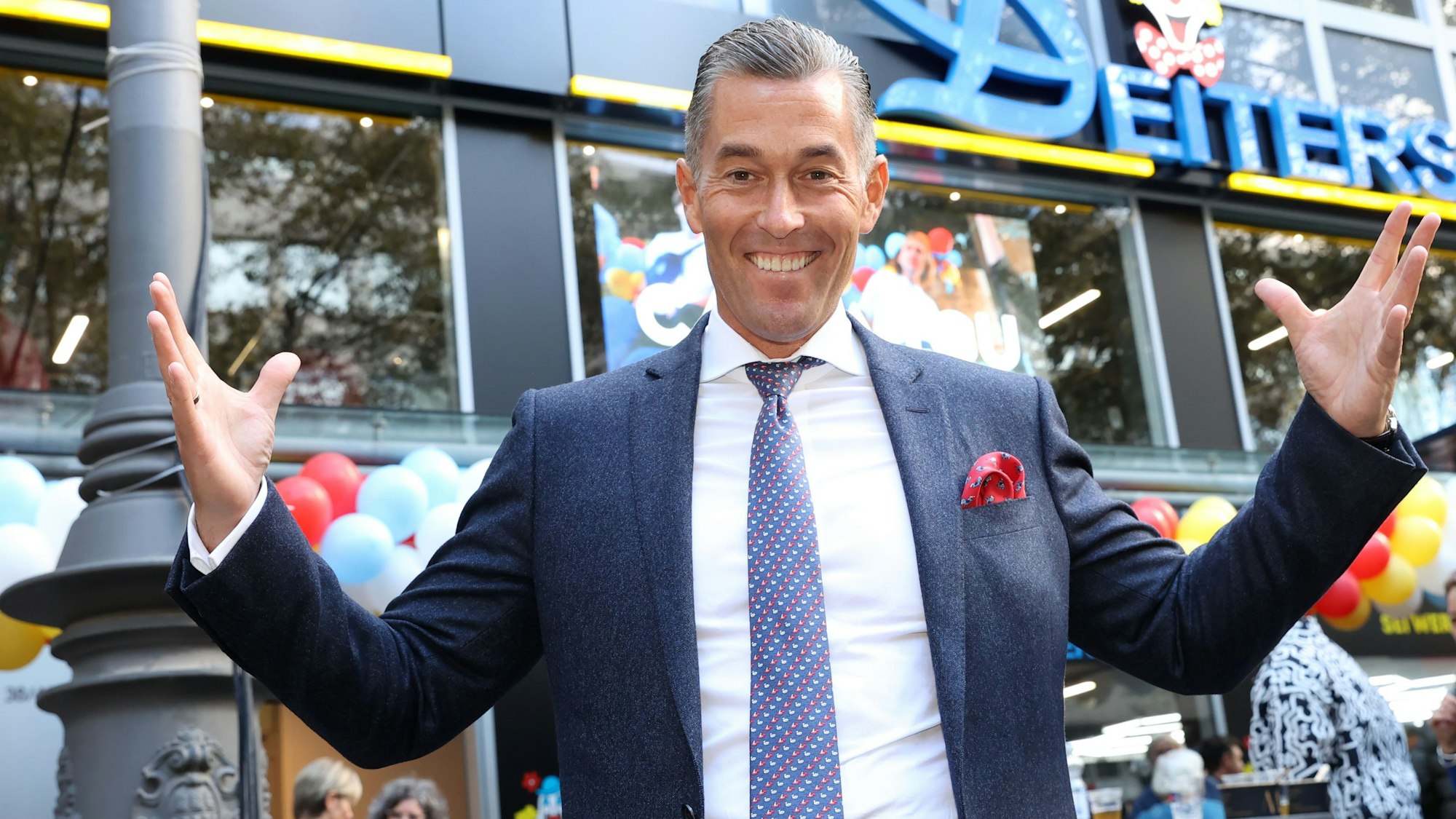 Herbert Geiss steht vor einer Deiters-Filial in Köln.