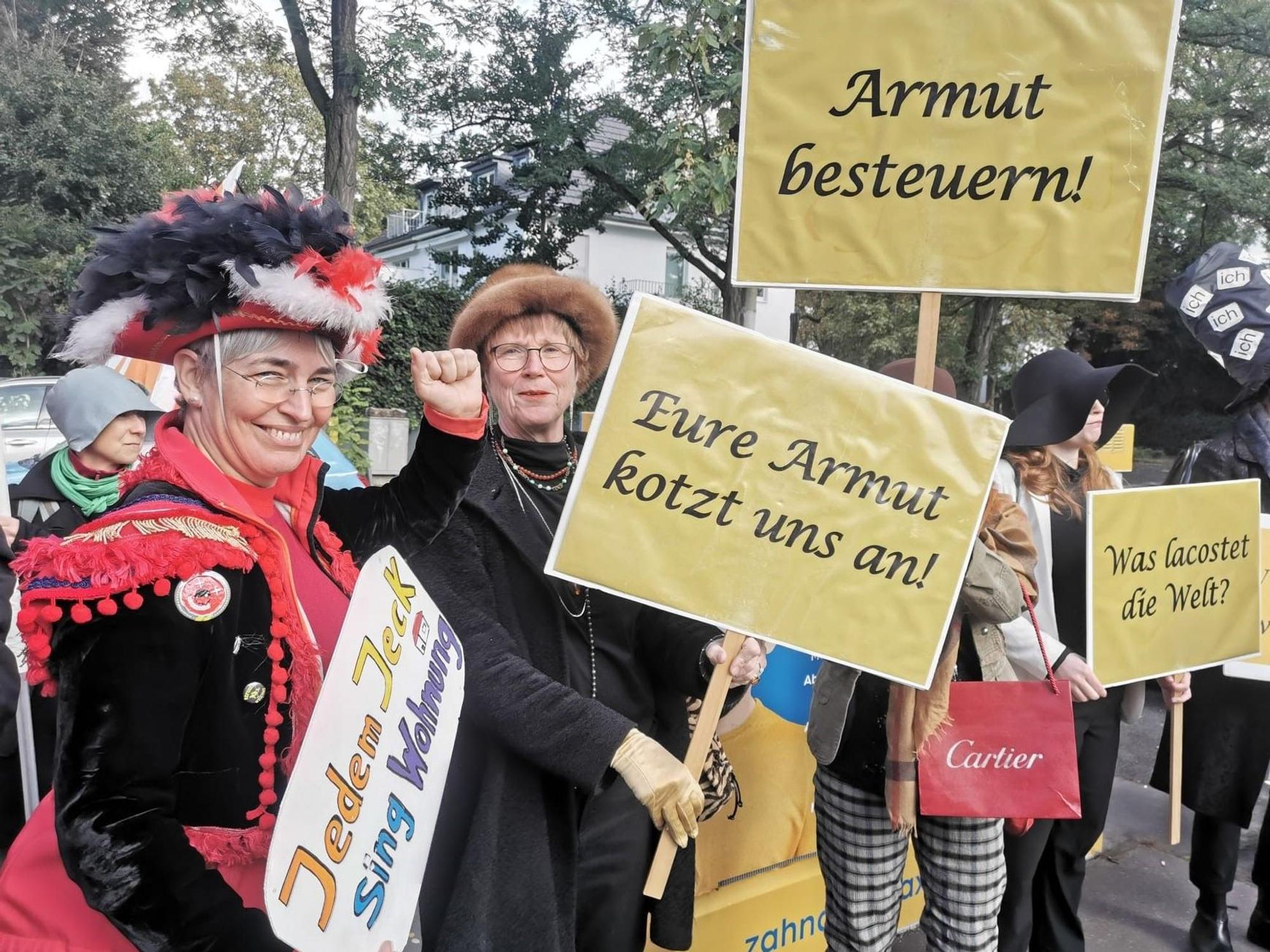 Mehrere Menschen halten Plakate hoch, darauf steht unter anderem „Eure Armut kotzt uns an“.