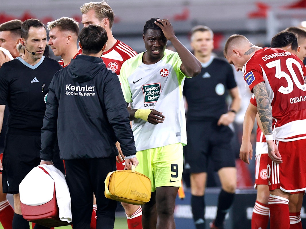 Kaiserslauterns Ragnar Ache hält sich im Spiel bei Fortuna Düsseldorf nach einem Flaschenwurf den Kopf.