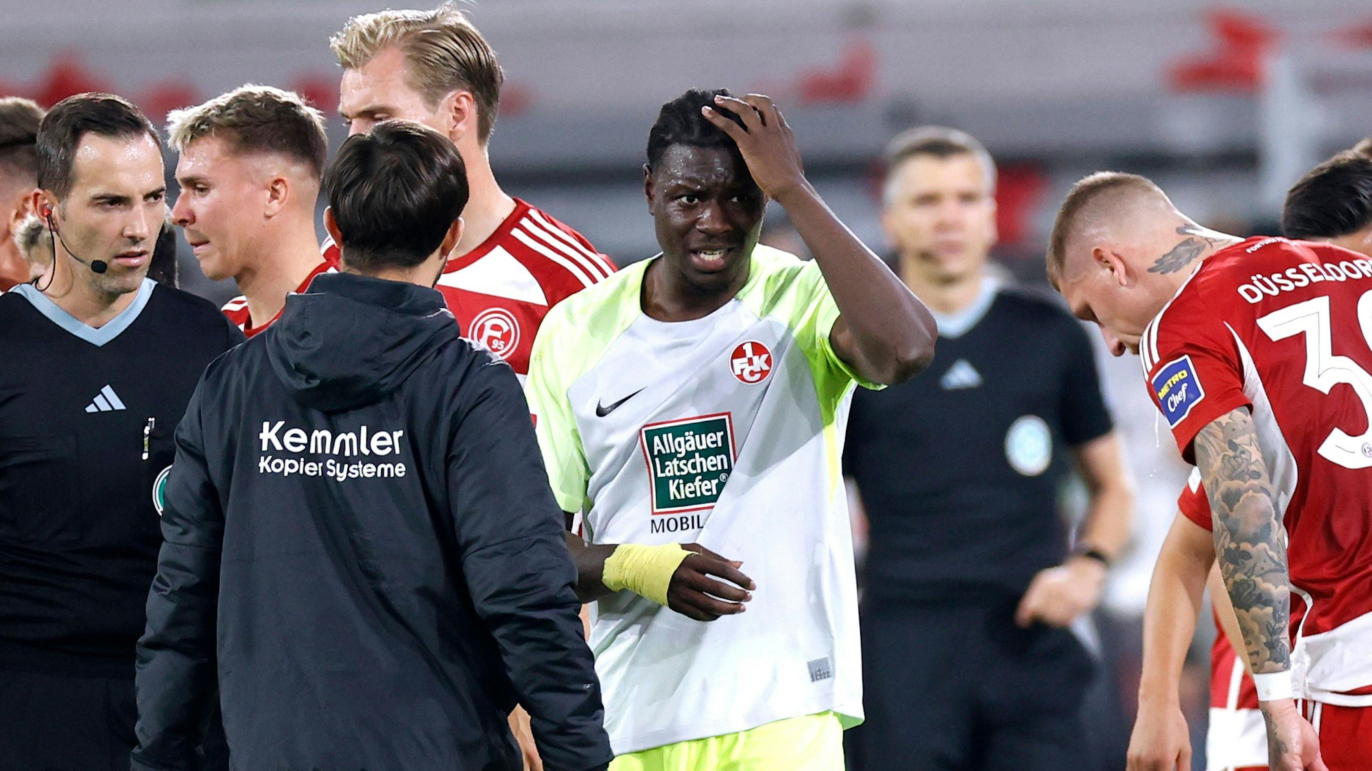 Kaiserslauterns Ragnar Ache hält sich im Spiel bei Fortuna Düsseldorf nach einem Flaschenwurf den Kopf.