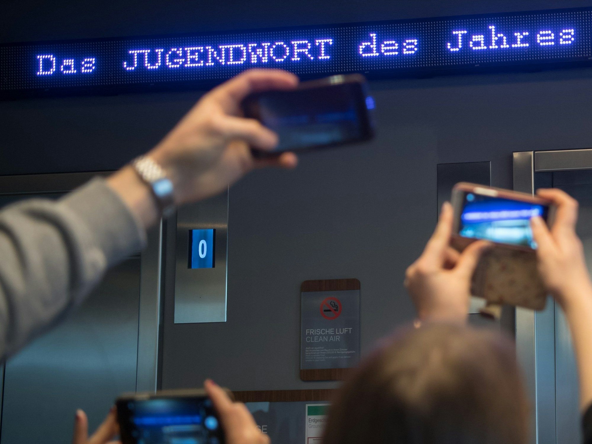 Auf einem Laufband erscheint „Jugendwort des Jahres“ über den digitalen Newsticker eines Hotels.