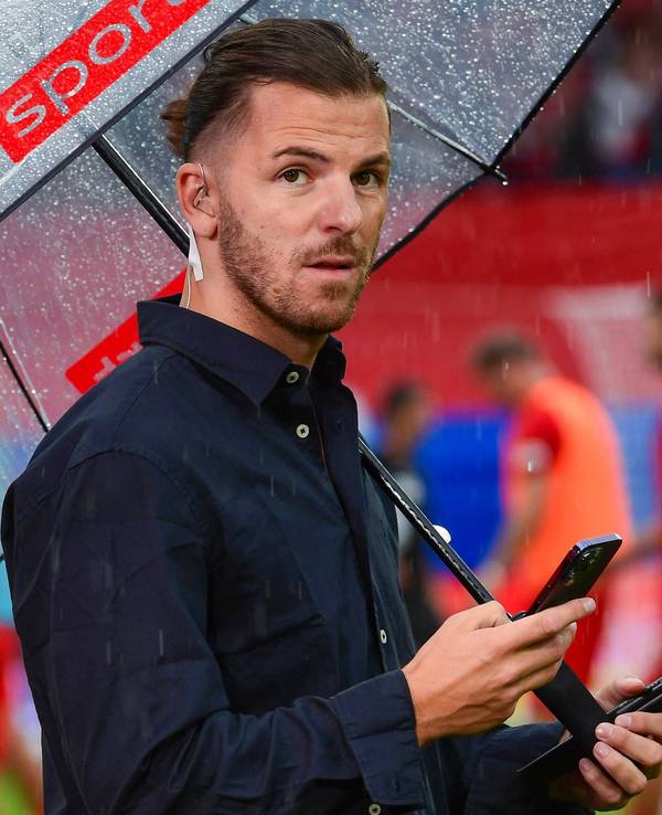 Riccardo Basile steht bei einem TV-Einsatz für Sky unter einem Regenschirm.