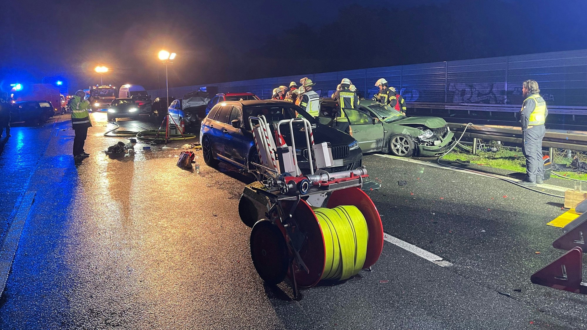 Feuerwehr und Polizei stehen an einer Unfallstelle auf einer Autobahn.