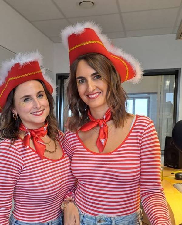 Zwei Frauen in rot-weißen Ringelshirts stehen in einem Studio und lächeln in die Kamera.
