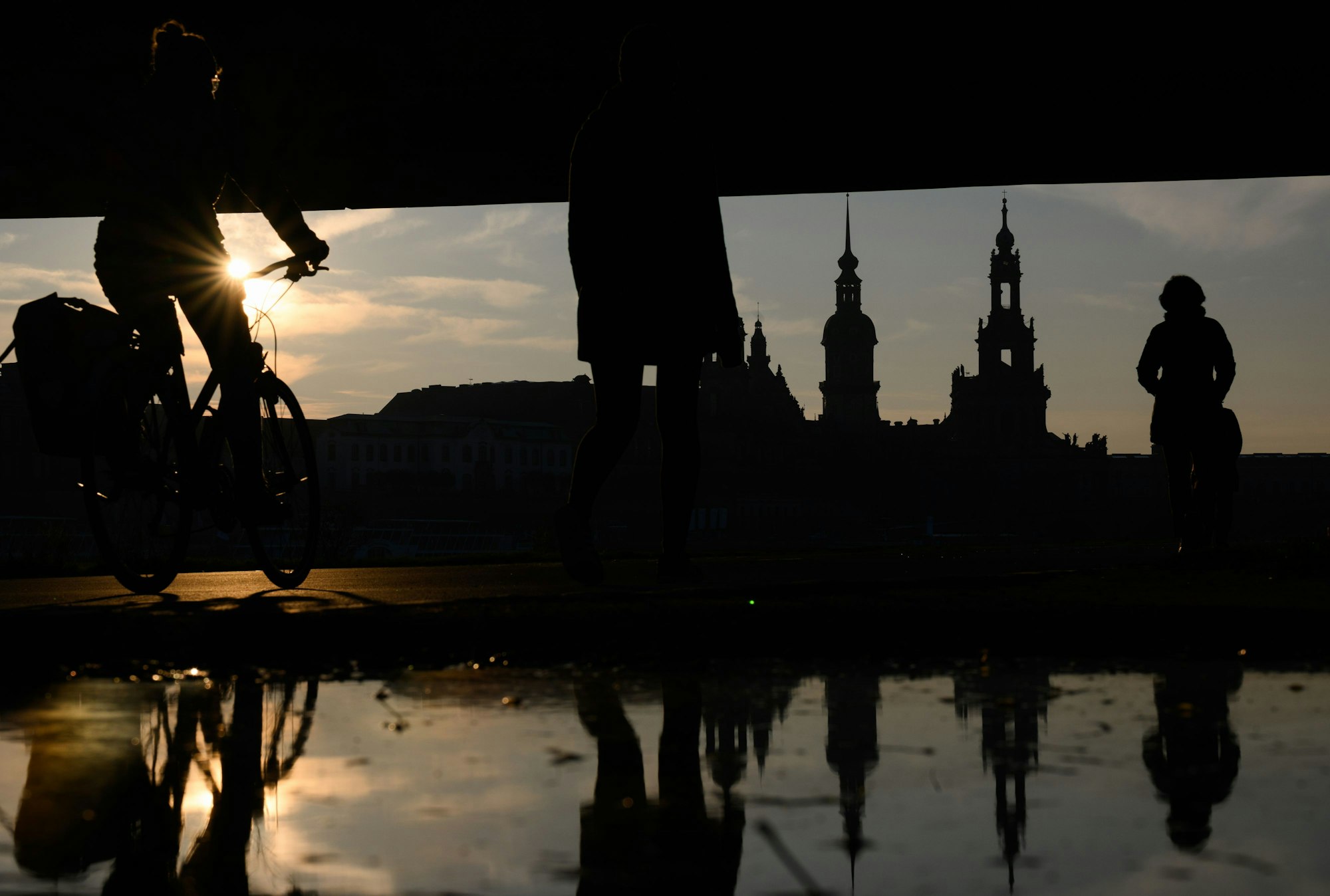 Fahrradfahrende und Fußgänger sind am Nachmittag in Dresden auf dem Elberadweg unterhalb der Carolabrücke gegenüber der historischen Altstadtkulisse unterwegs.