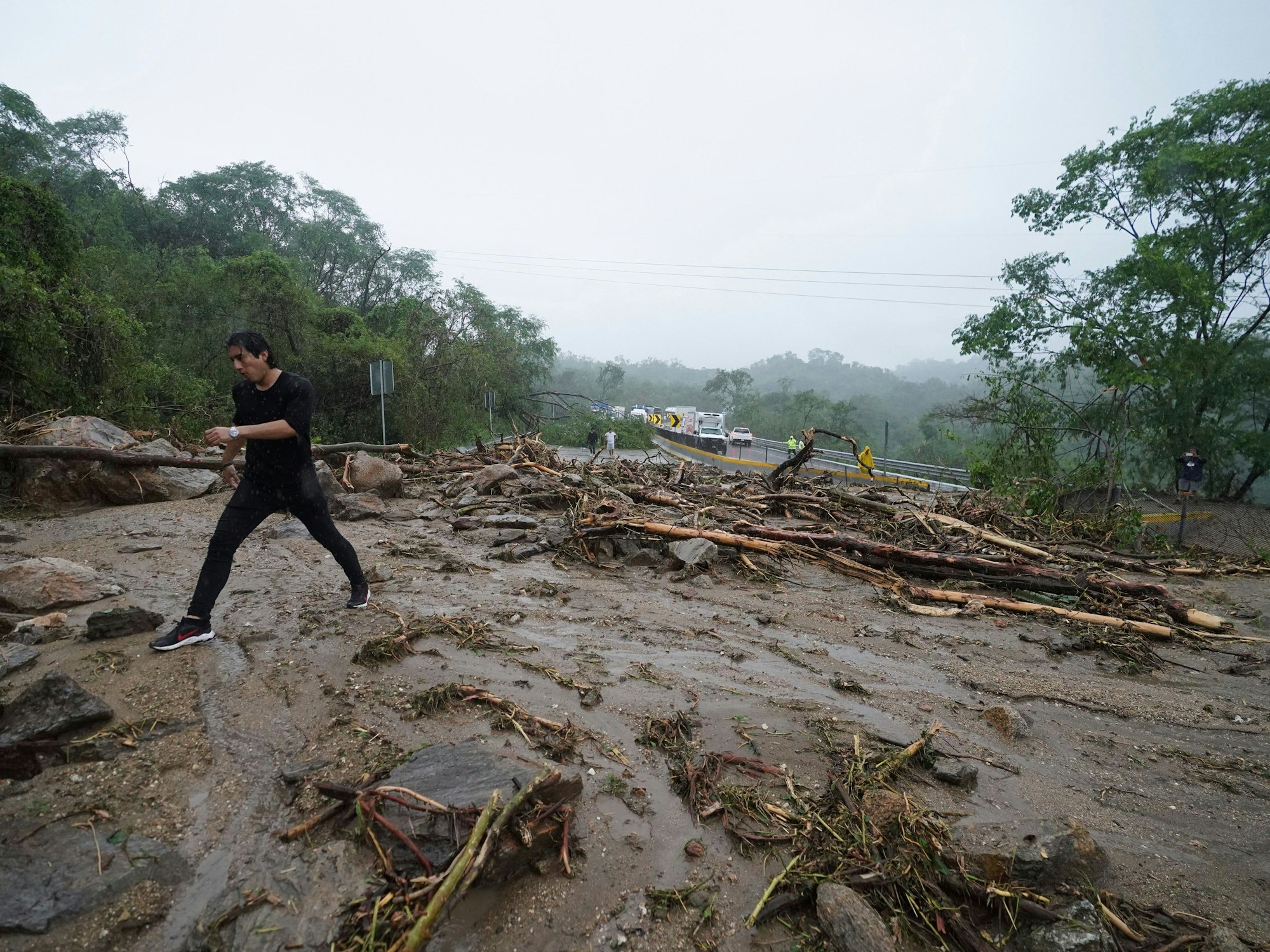 Ein Mann überquert eine Straße, die durch einen vom Hurrikan „Otis“ ausgelösten Erdrutsch in der Nähe von Acapulco blockiert ist.