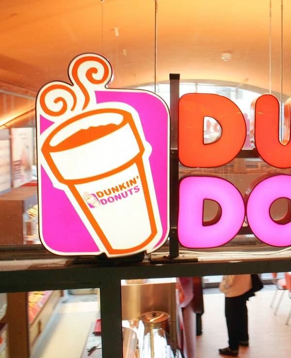 Das Firmenlogo klebt an der Fensterscheibe einer Filiale der amerikanischen Donut-Kette Dunkin' Donuts, aufgenommen in Berlin.