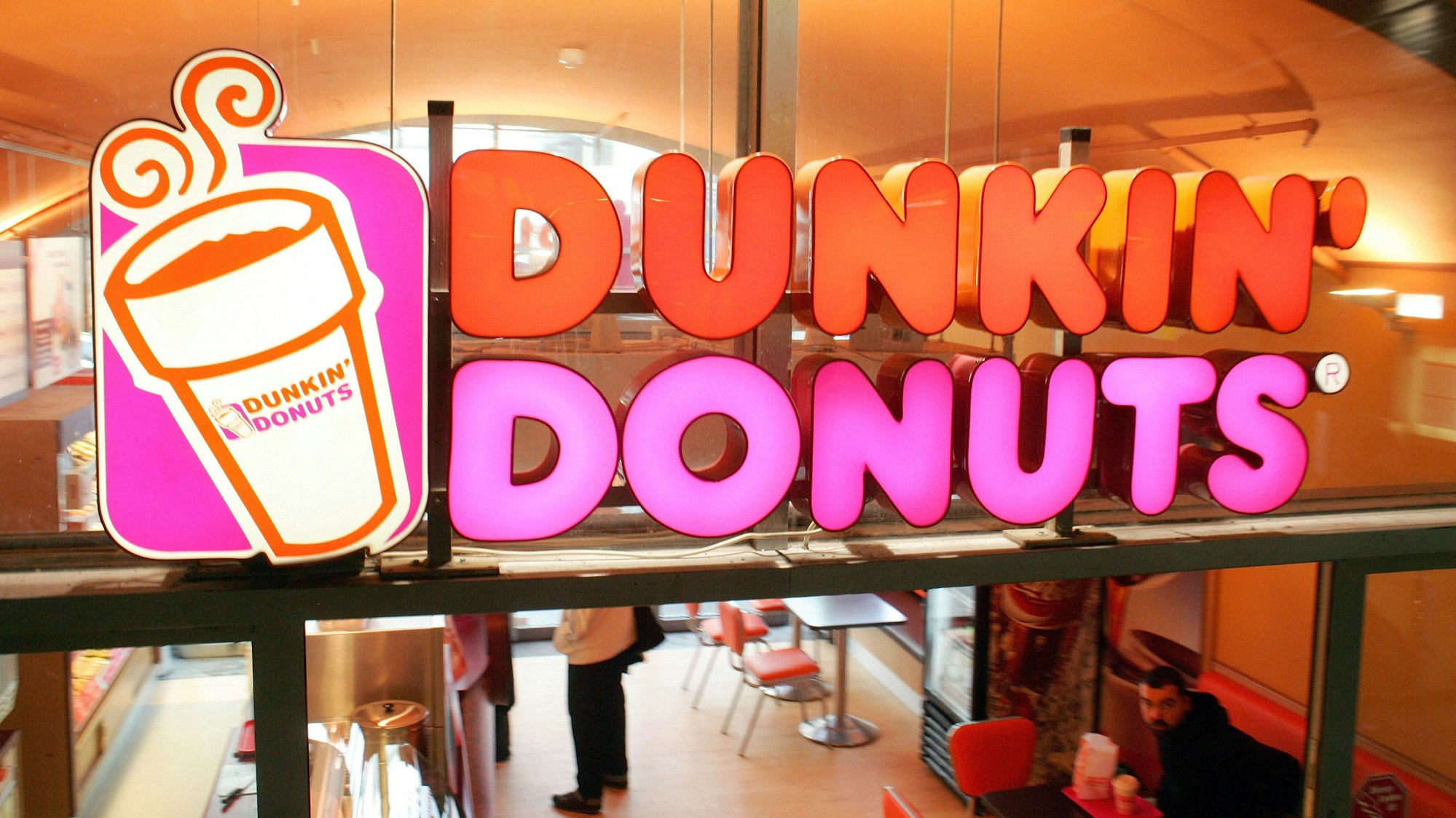 Das Firmenlogo klebt an der Fensterscheibe einer Filiale der amerikanischen Donut-Kette Dunkin' Donuts, aufgenommen in Berlin.