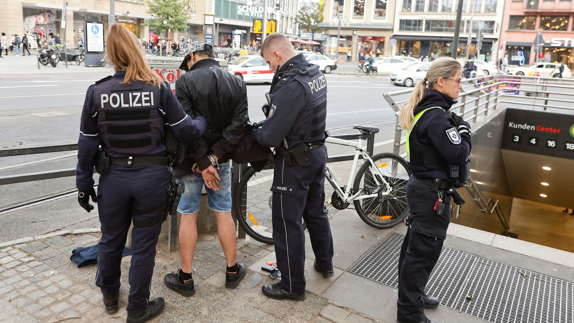 Einsatzkräfte der Polizei legen einem Mann am Neumarkt Handschellen an.