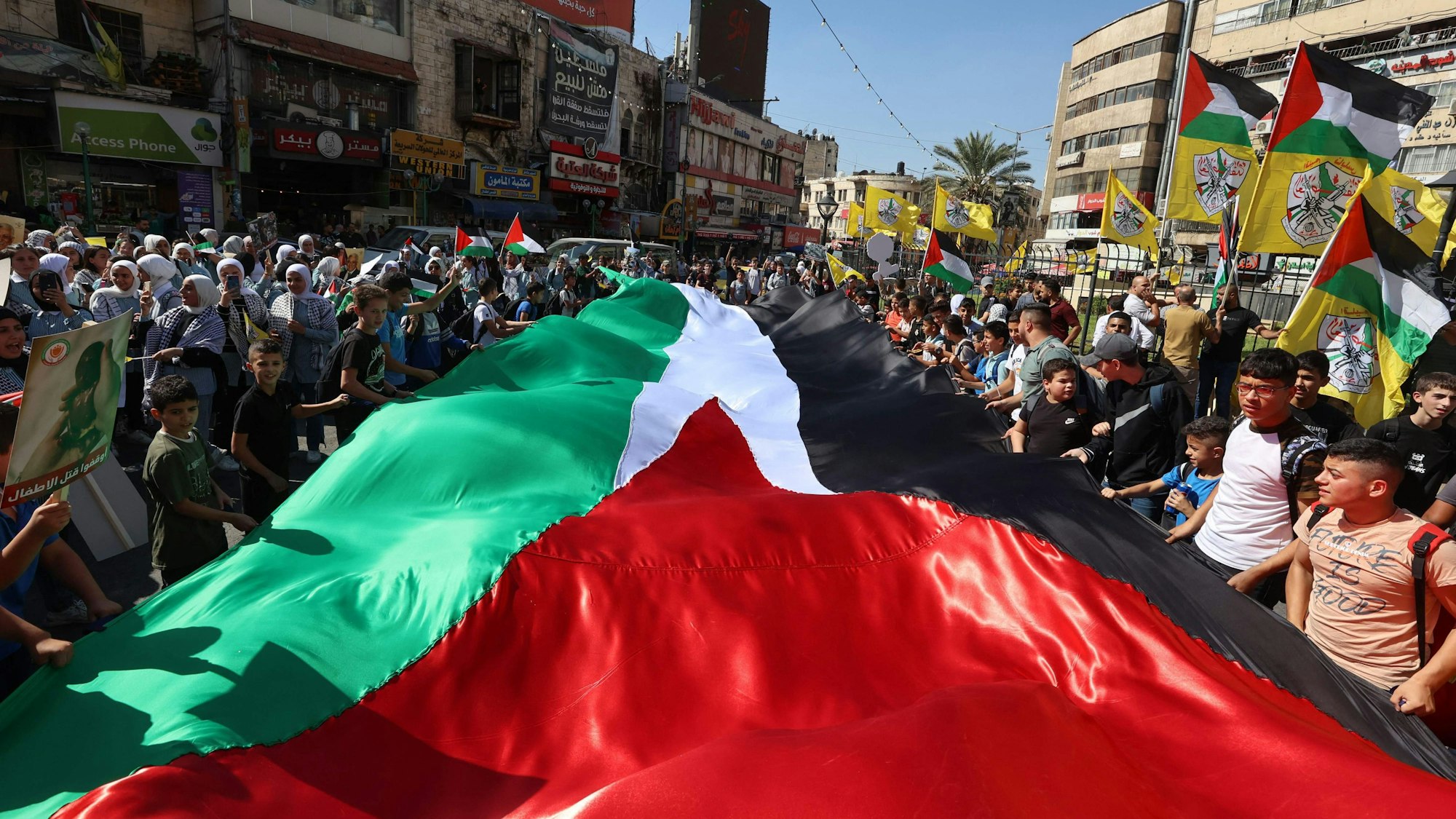 Menschen schwenken eine große palästinensische Flagge, als sie am 26. Oktober in Nablus im Westjordanland demonstrieren. Die islamistische Hamas hat im Gazastreifen erneut zu Protesten aufgerufen.