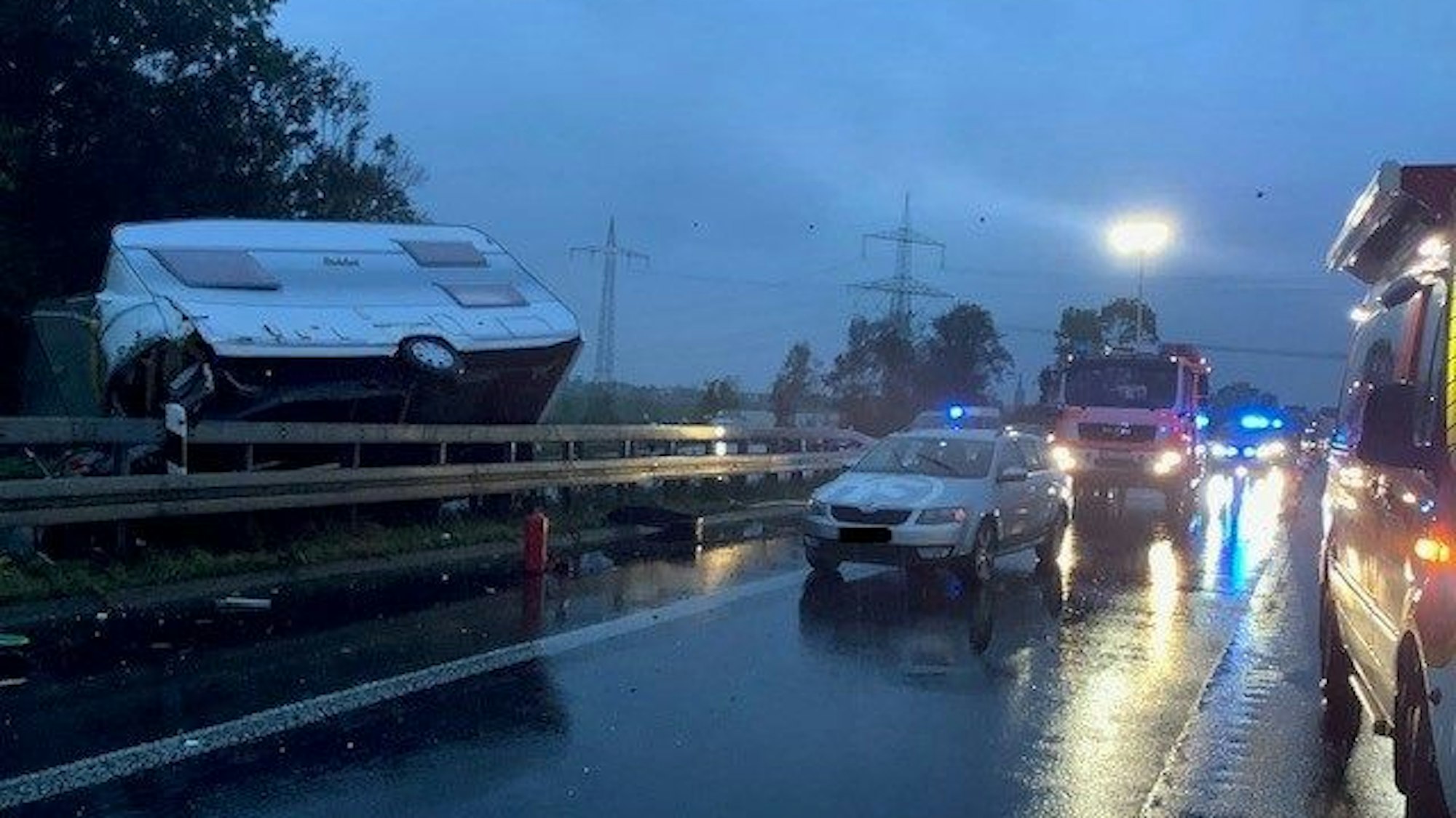 Foto von einem Unfall auf einer Autobahn: Ein Wohnwagen liegt quer über der Leitplanke.