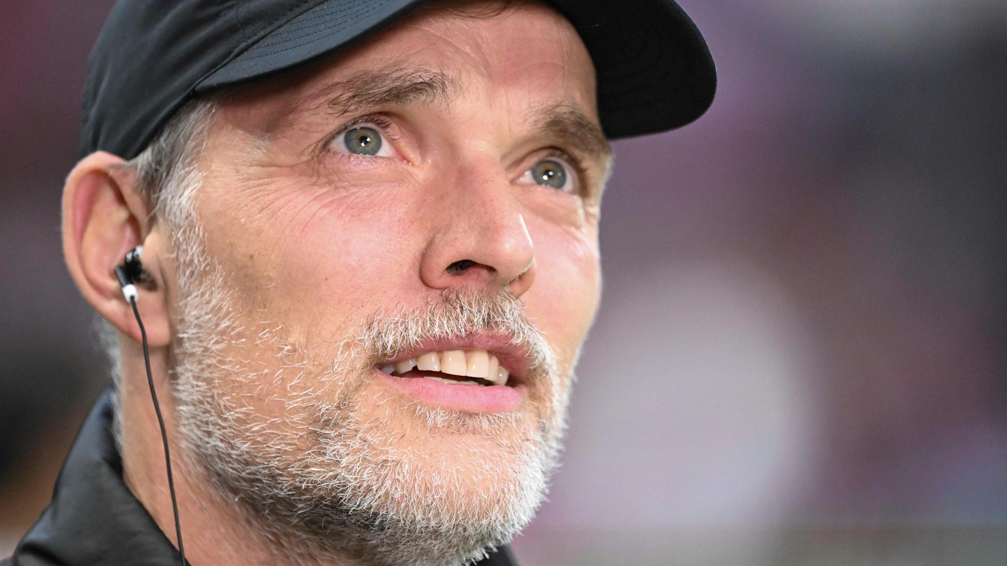 Thomas Tuchel steht vor dem Spiel für ein Interview bereit. Er trägt eine Kappe und hat einen Kopfhörer im Ohr.