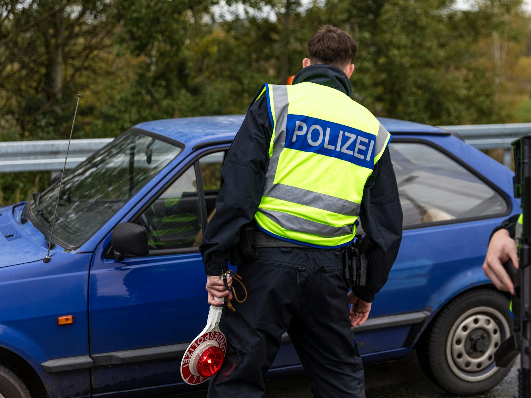 Ein Beamter der Bundespolizei spricht mit dem Fahrer eines Pkw an der Autobahn.