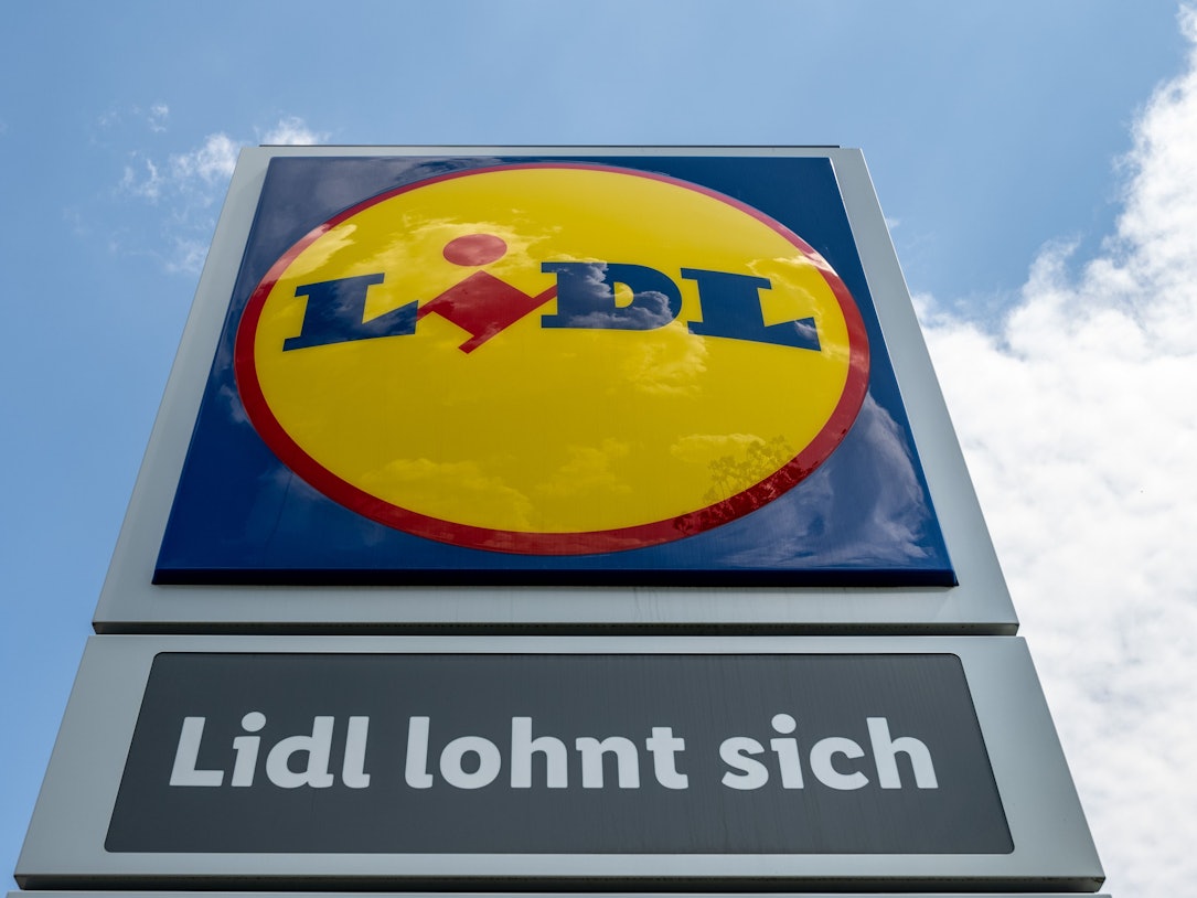 Eine Stele mit dem Logo des Discounters Lidl steht vor einer Filiale.
