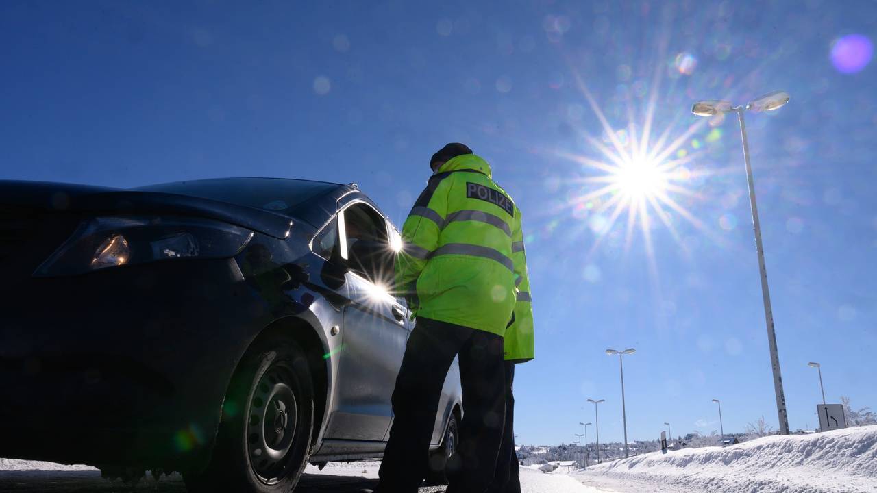 Zwei Bundespolizisten kontrollieren im Rahmen von Grenzkontrollen der Bundespolizei an der deutsch-tschechischen Grenze die Personalien eines Autofahrers.