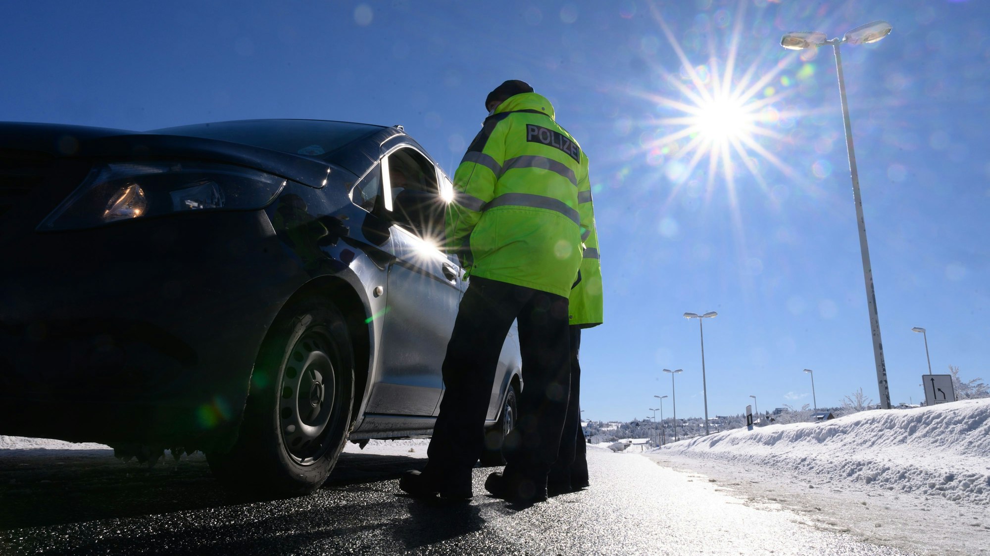 Zwei Bundespolizisten kontrollieren im Rahmen von Grenzkontrollen der Bundespolizei an der deutsch-tschechischen Grenze die Personalien eines Autofahrers.