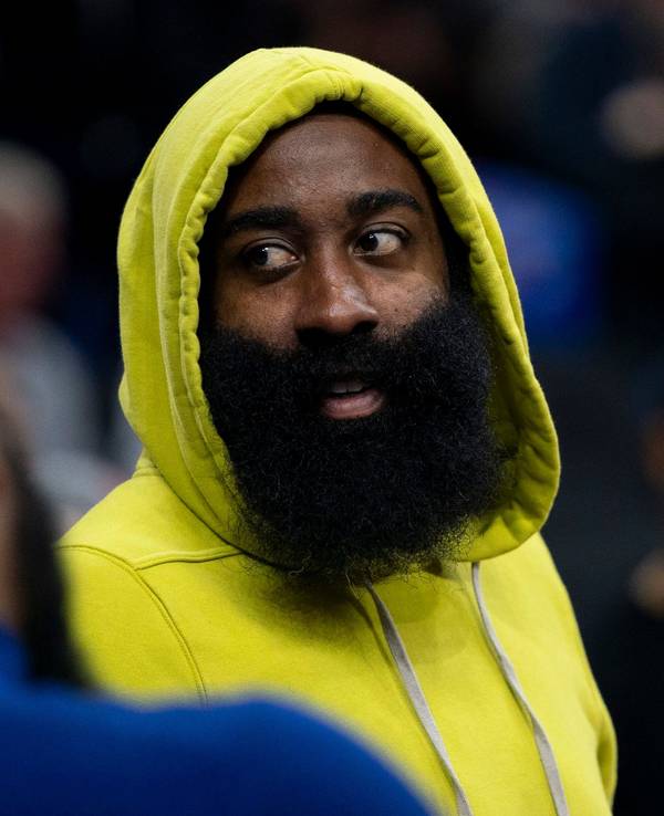 James Harden guckt sich das Spiel der 76ers gegen die Portland Trail Blazers als Zuschauer an. Er trägt einen gelben Hoodie und hat die Kapuze über den Kopf gezogen.