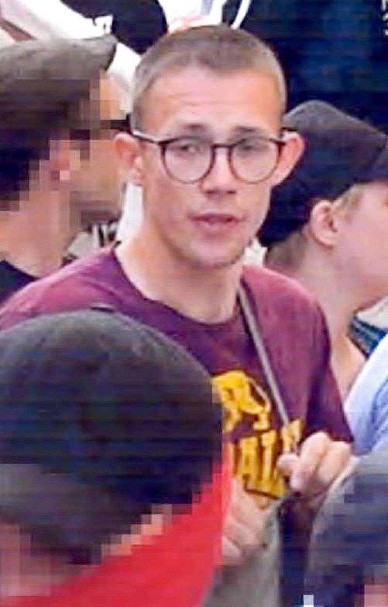 Junger Mann mit Brille und rotem Shirt auf einem Fahndungsfoto.