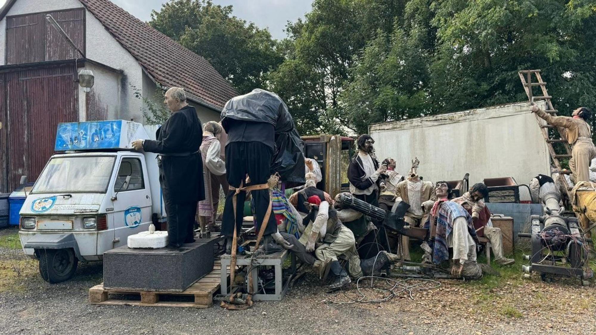Diverse Figuren aus dem Phantasialand stehen wie auf einer Müllkippe in einem Hinterhof.