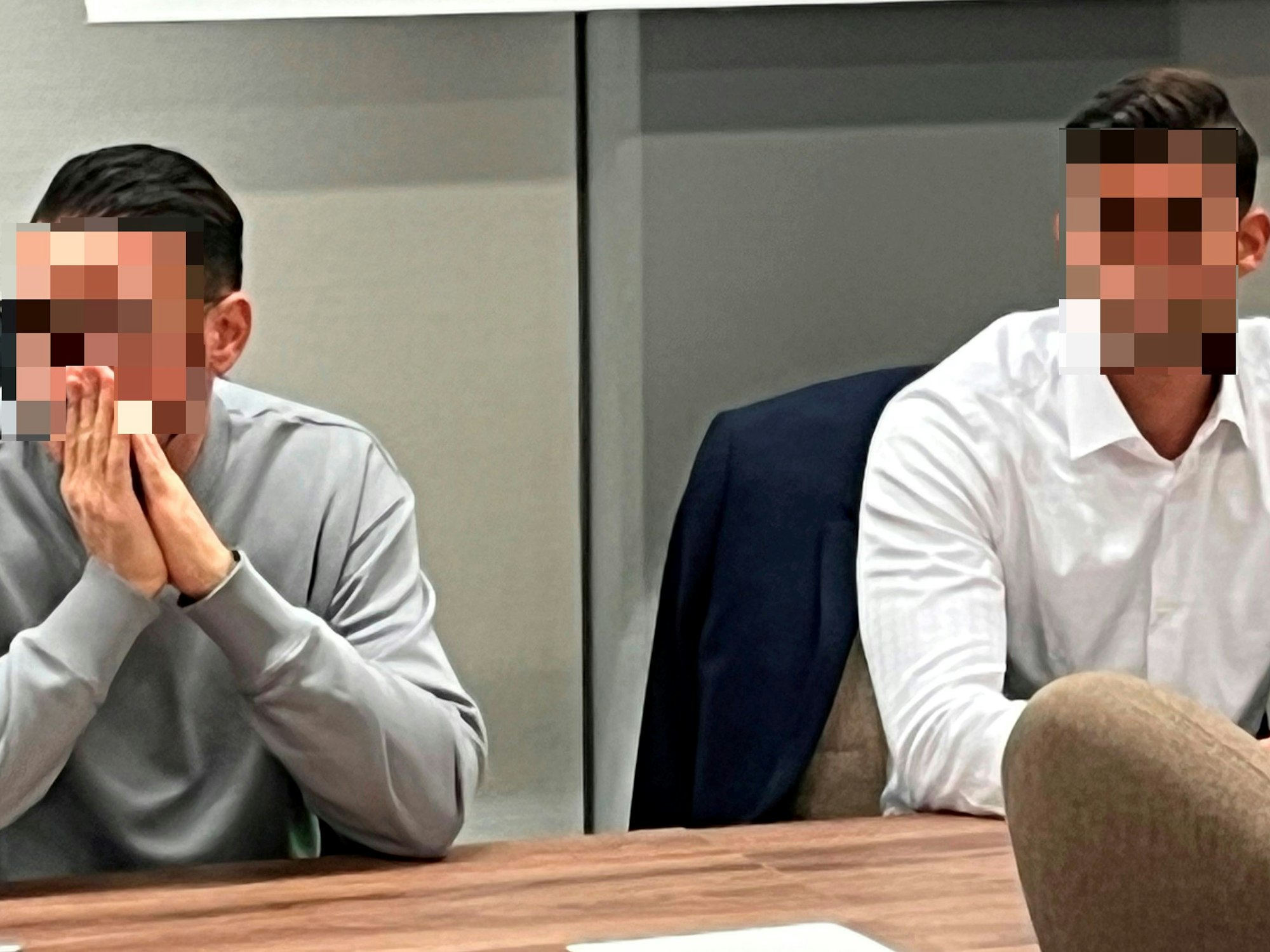 Zwei Männer sitzen nebeneinander auf der Anklagebank.