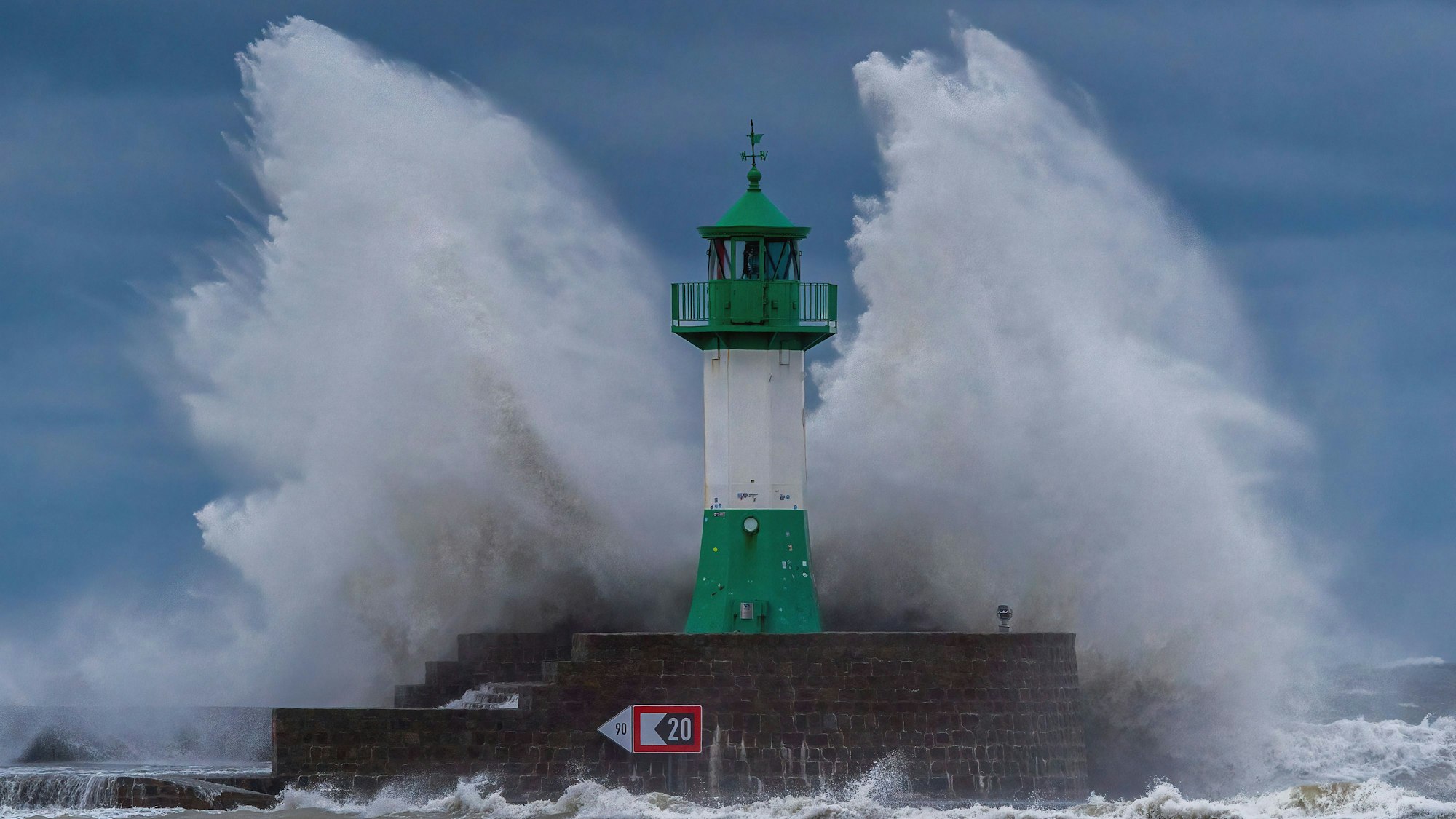 Wellen der Ostsee peitschen bei einem schweren Sturmtief an den Leuchtturm auf der Ostmole.