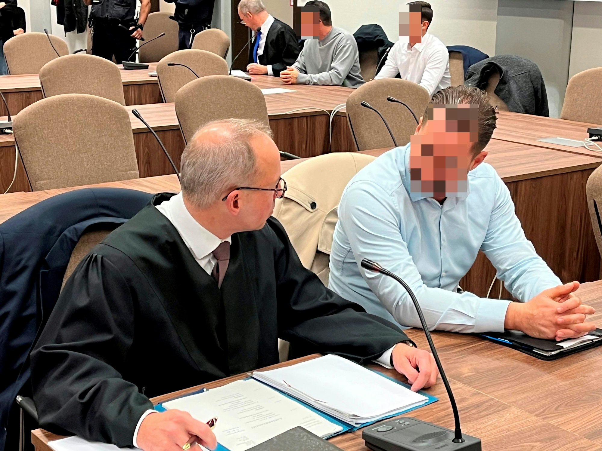 Anwalt Martin Kretschmer spricht mit seinem Mandanten, der neben ihm sitzt.