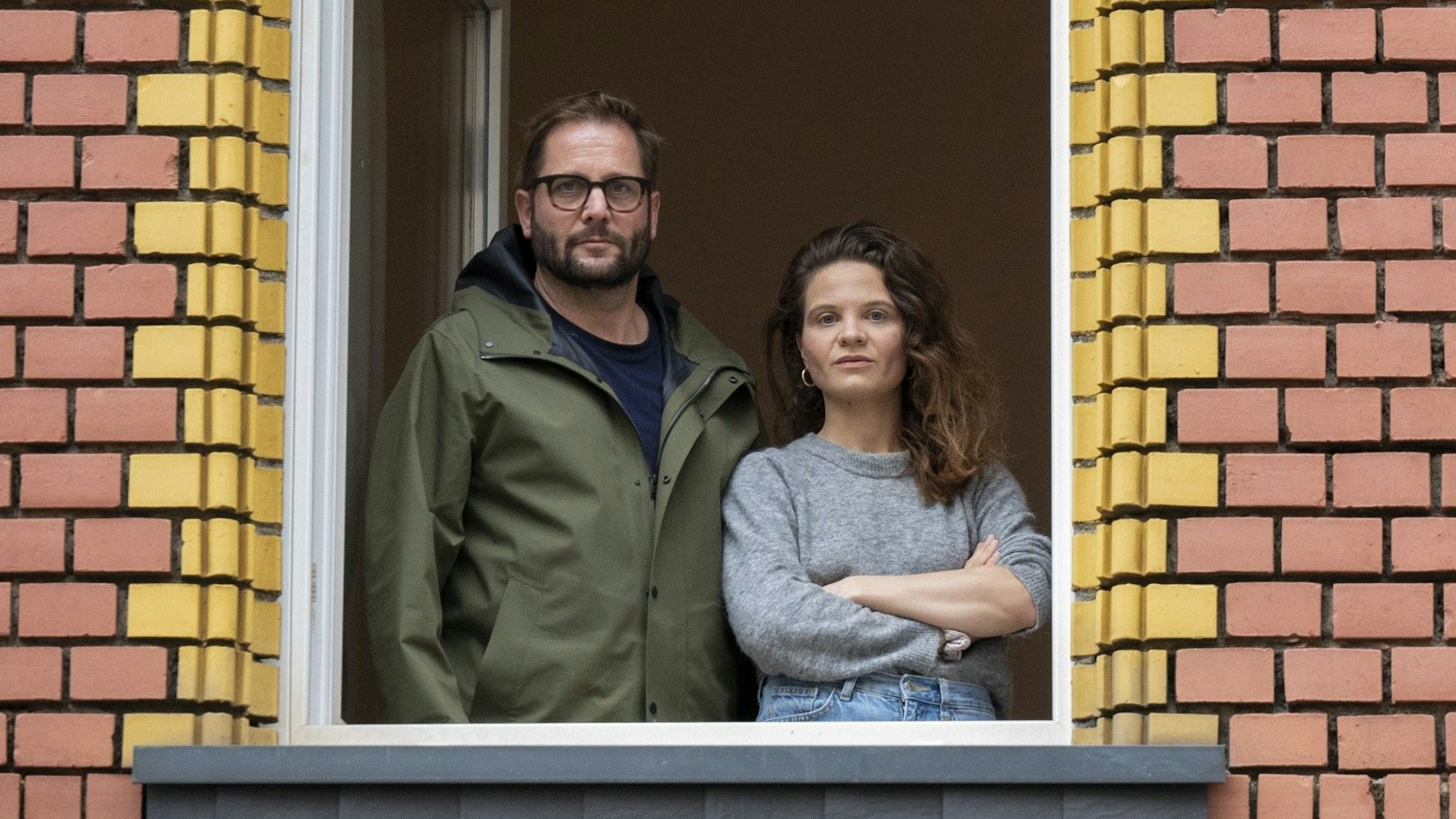Lynn Busch und Hannes Kleinknecht stehen am Fenster ihrer Wohnung.