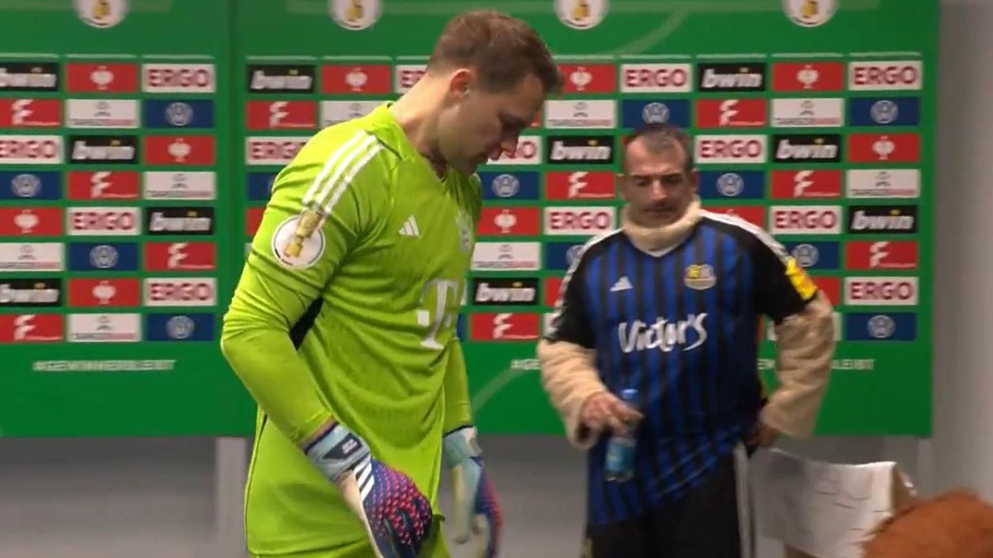 Hinter Manuel Neuer ist beim Spiel im DFB-Pokal zwischen dem 1. FC Saarbrücken und dem FC Bayern München das Maskottchen der Gastgeber ohne seinen Löwenkopf zu sehen.