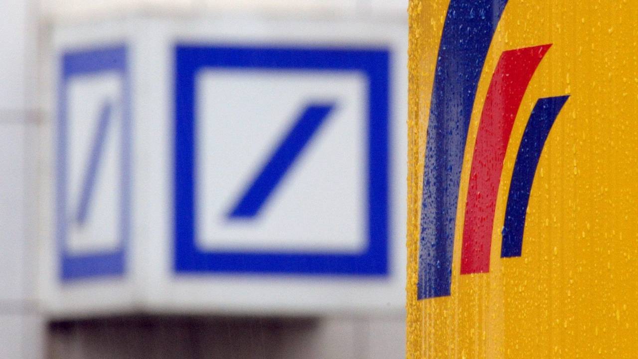 Das Logo einer Filiale der Deutschen Bank (l) und das Logo der auf der gegenüberliegenden Straßenseite befindlichen Postbank-Zentrale in Bonn.