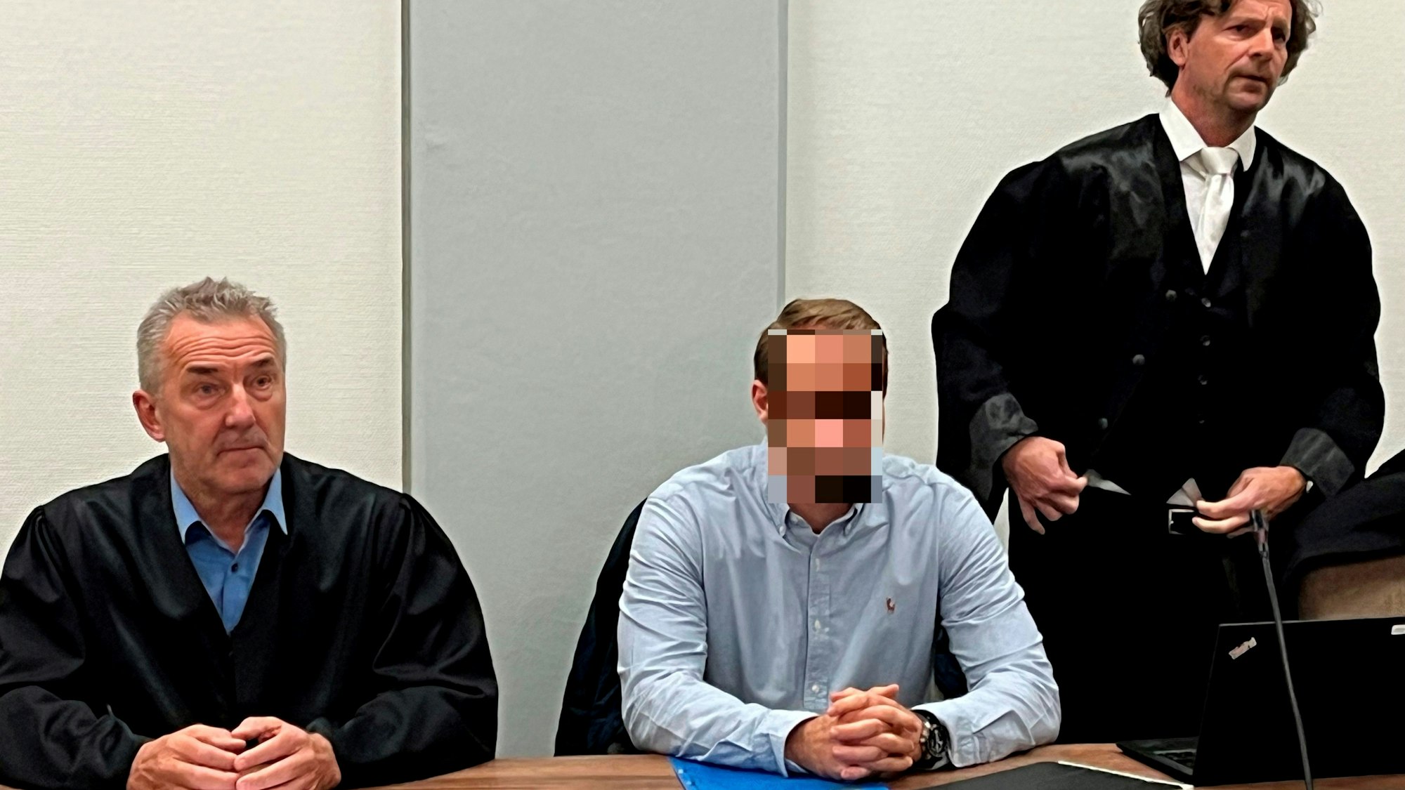 Ein Mann sitzt zwischen seinen beiden Anwälten.