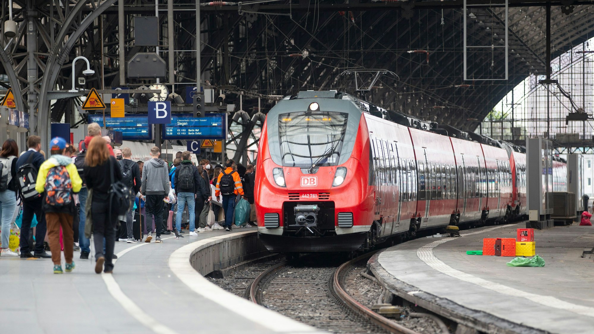 Bahnreisende warten auf dem Bahnsteig auf die Einfahrt eines Zuges im Kölner Hauptbahnhof.