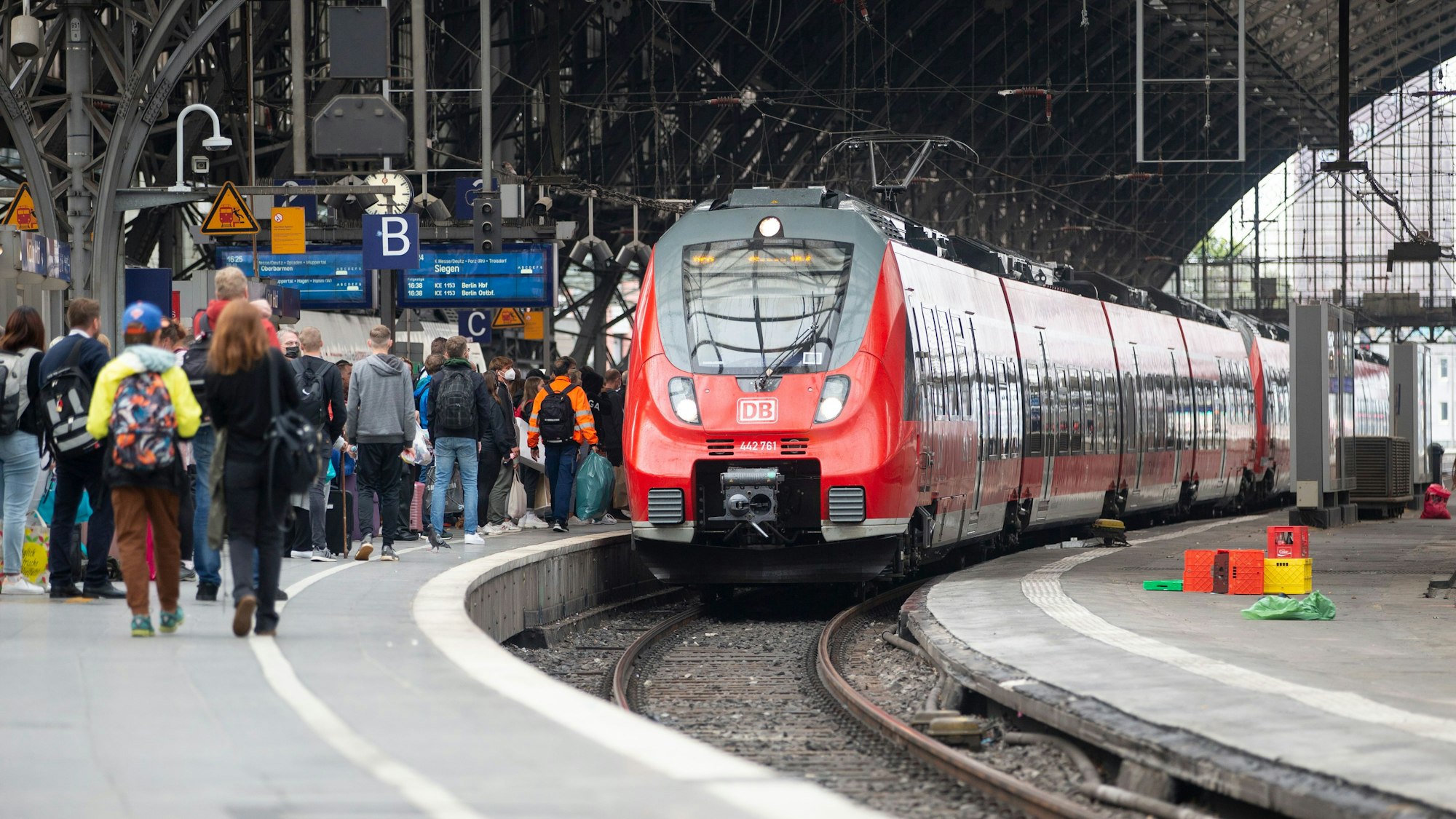Bahnreisende stehen im Kölner Hauptbahnhof am Gleis.