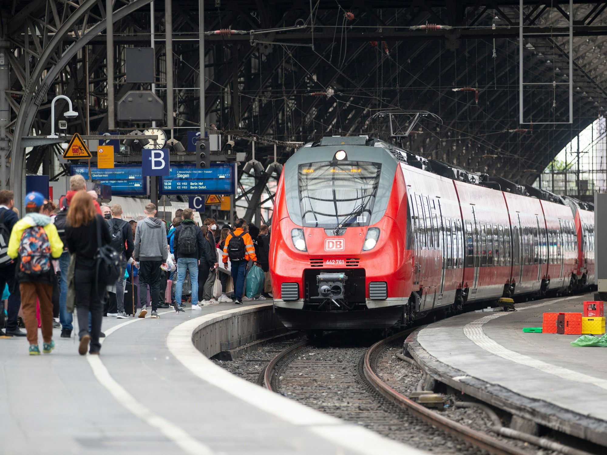 Bahnreisende warten auf dem Bahnsteig auf die Einfahrt des Zuges im Kölner Hauptbahnhof.