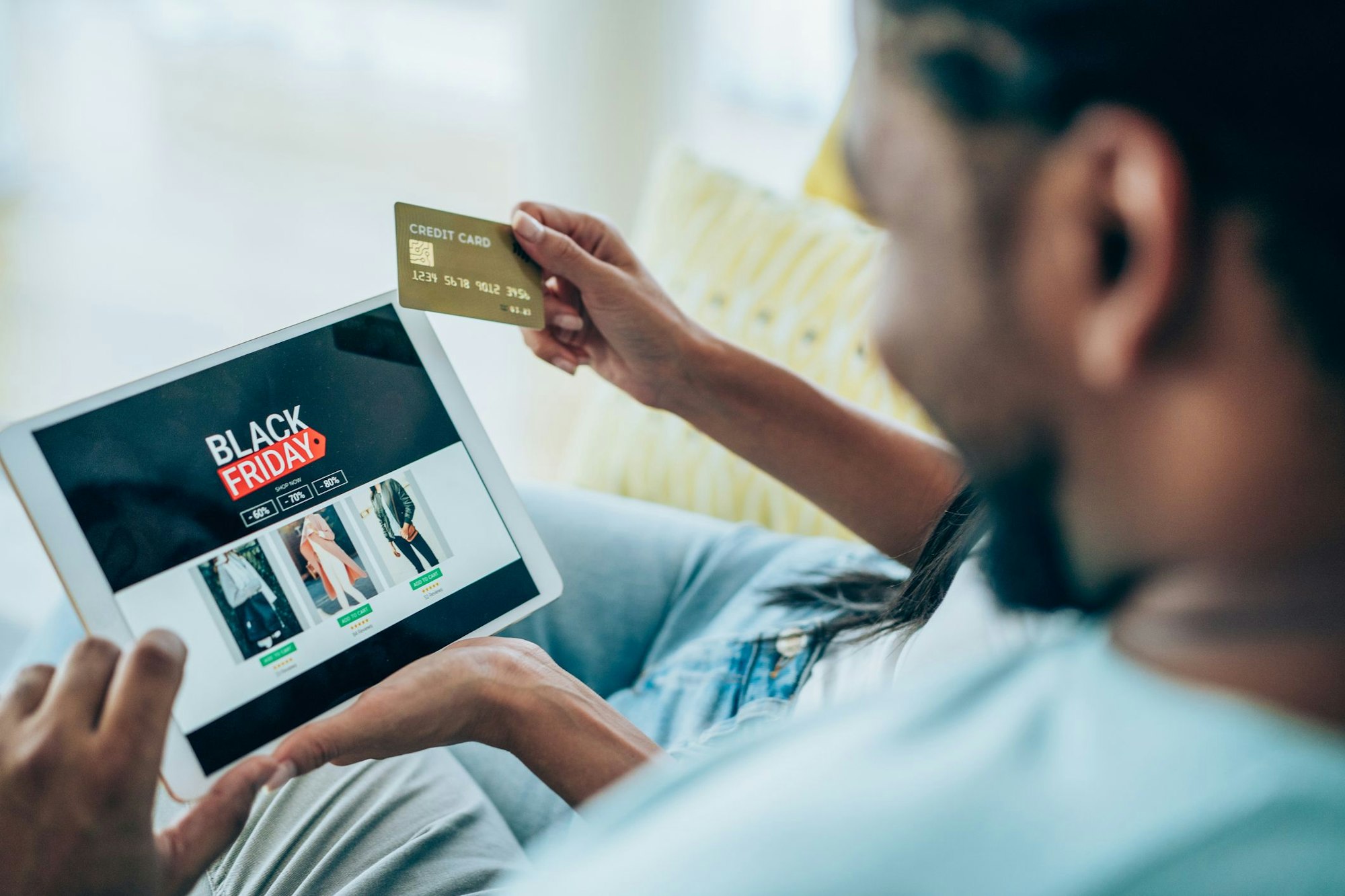 Close-up shot of a young couple holding a digital tablet and shopping online on Black Friday at home. Couple shopping online with credit card and digital tablet.