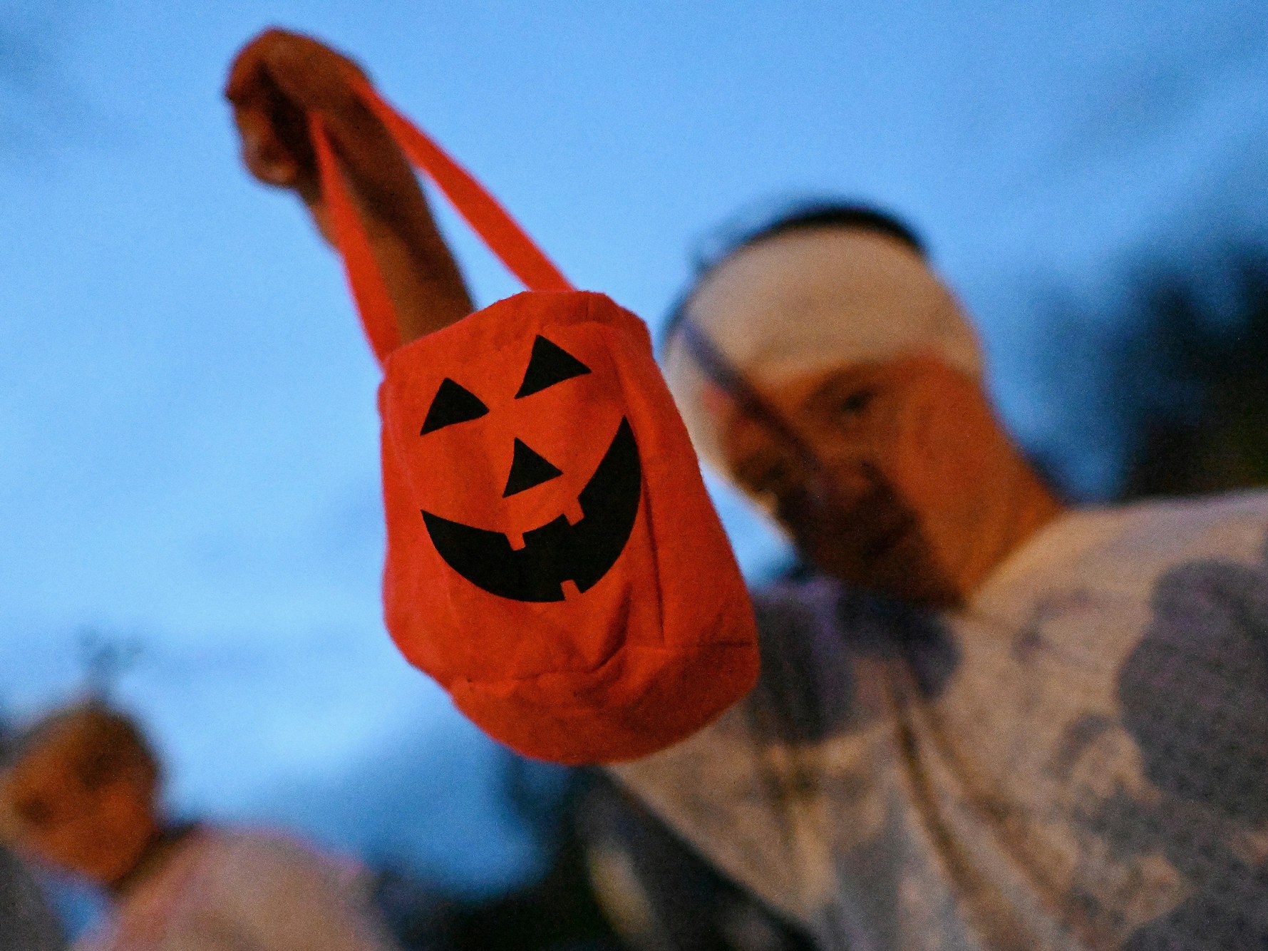 Ein Kind hält einen Beutel mit Kürbisdesign in die Kamera.