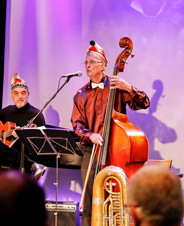 Eine Musikformation spielt auf einer kleinen Bühne, die Herren sind alle dunkel gekleidet.