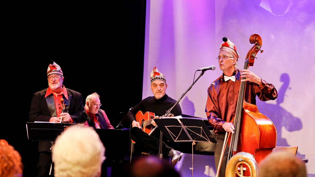 Eine Musikformation spielt auf einer kleinen Bühne, die Herren sind alle dunkel gekleidet.
