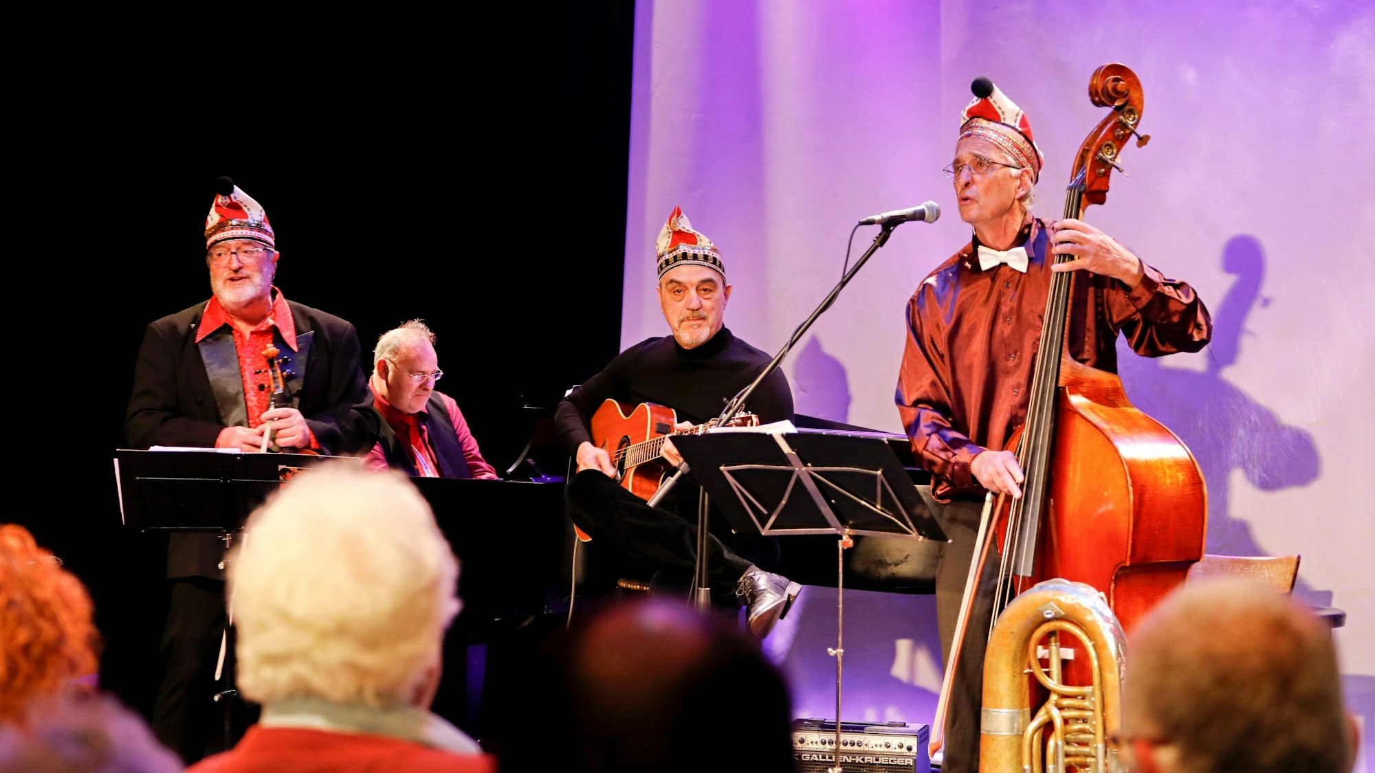 Eine Musikformation spielt auf einer kleinen Bühne, die Herren sind alle dunkel gekleidet.