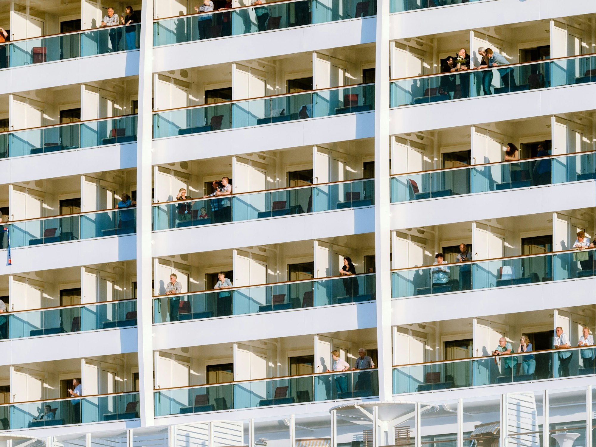 Kreuzfahrtreisende auf ihren Kabinenbalkonen an Bord des Kreuzfahrtschiffs AIDAprima.