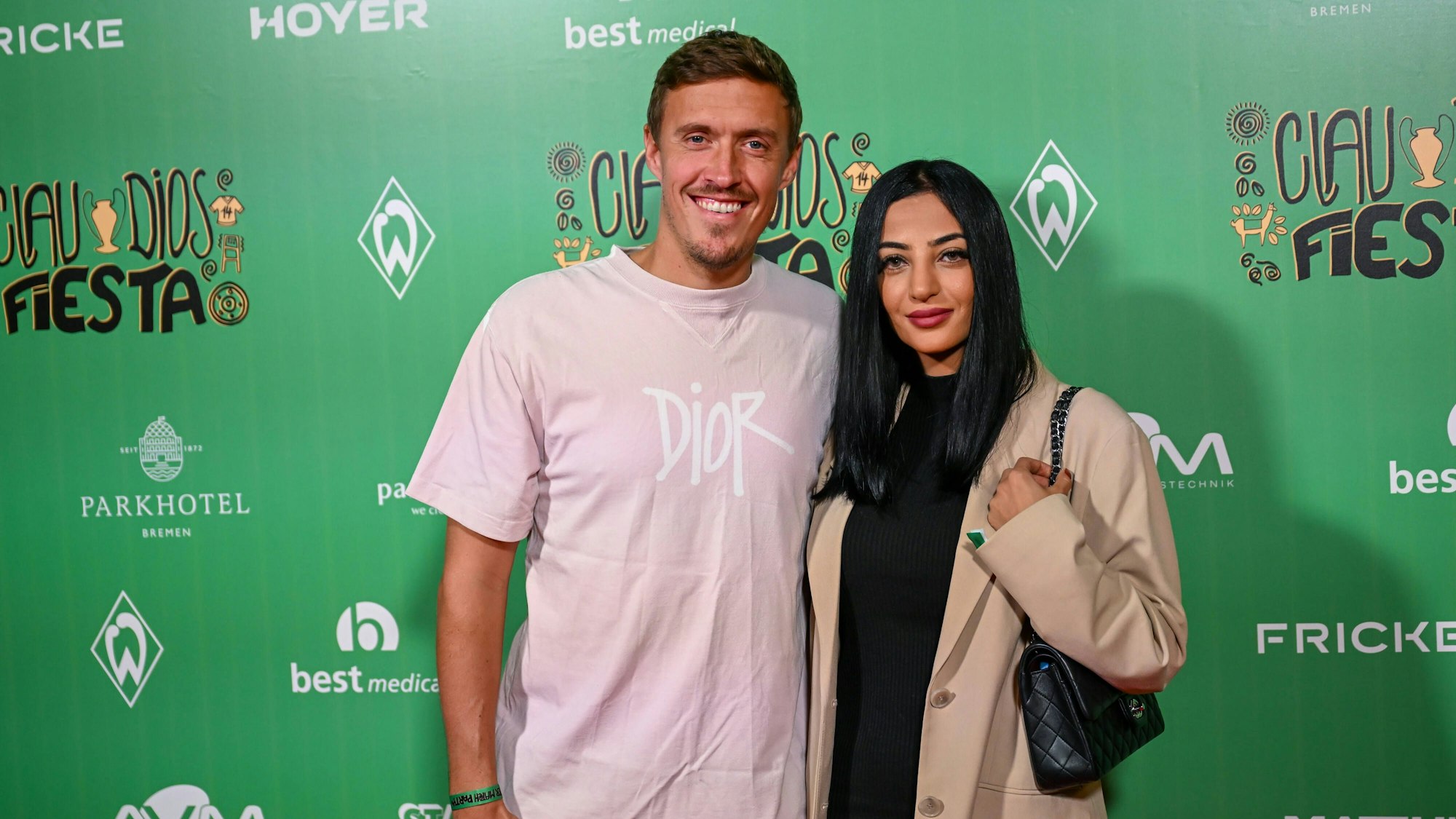 Das Foto zeigt Max und Dilara Kruse im Bremer Wohninvest Weserstadion vor einer Wand mit dem Logos des SV Werder Bremen und einigen Sponsoren des Fußballklubs.