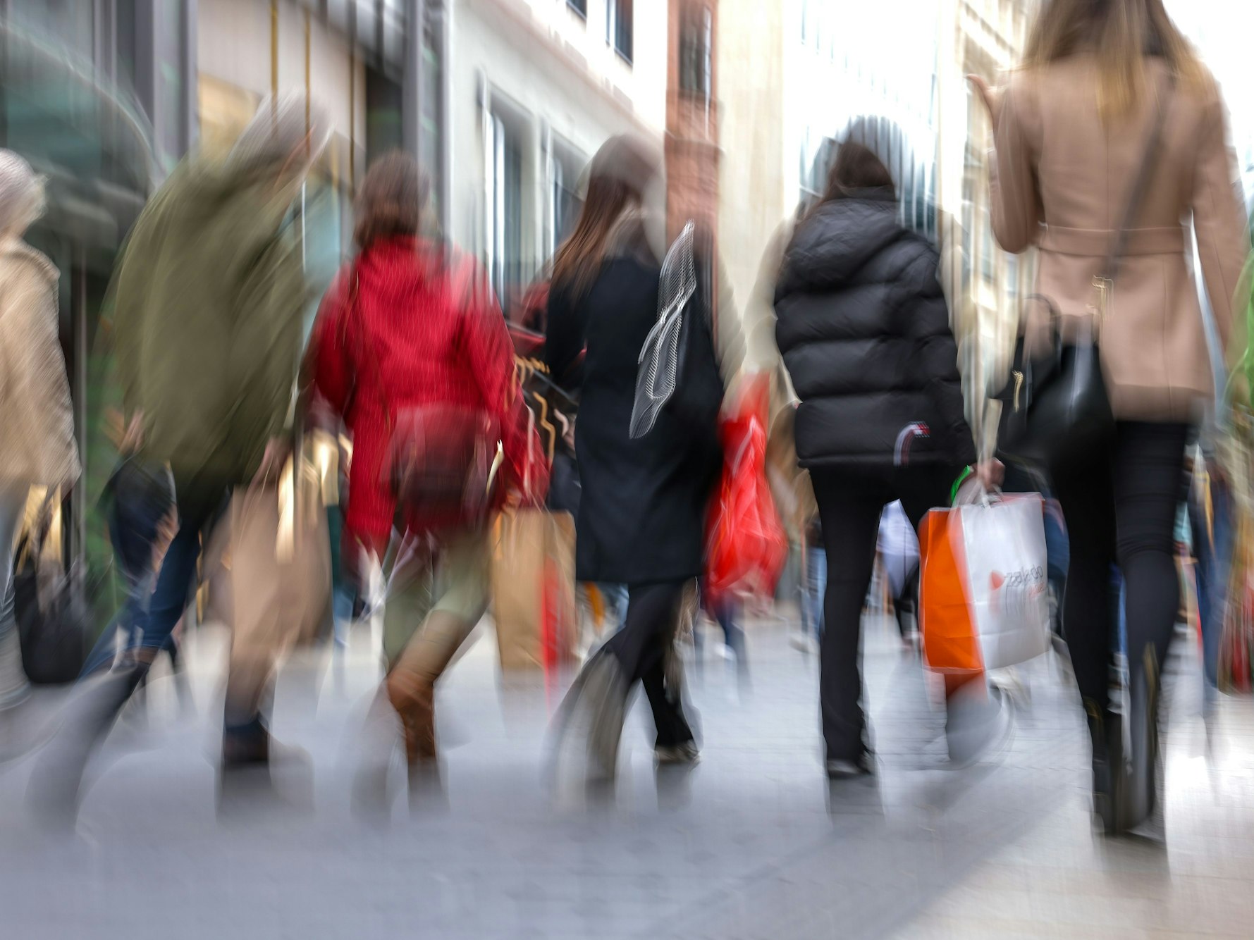 Passanten gehen mit mehreren Einkaufstüten durch die Leipziger Innenstadt.