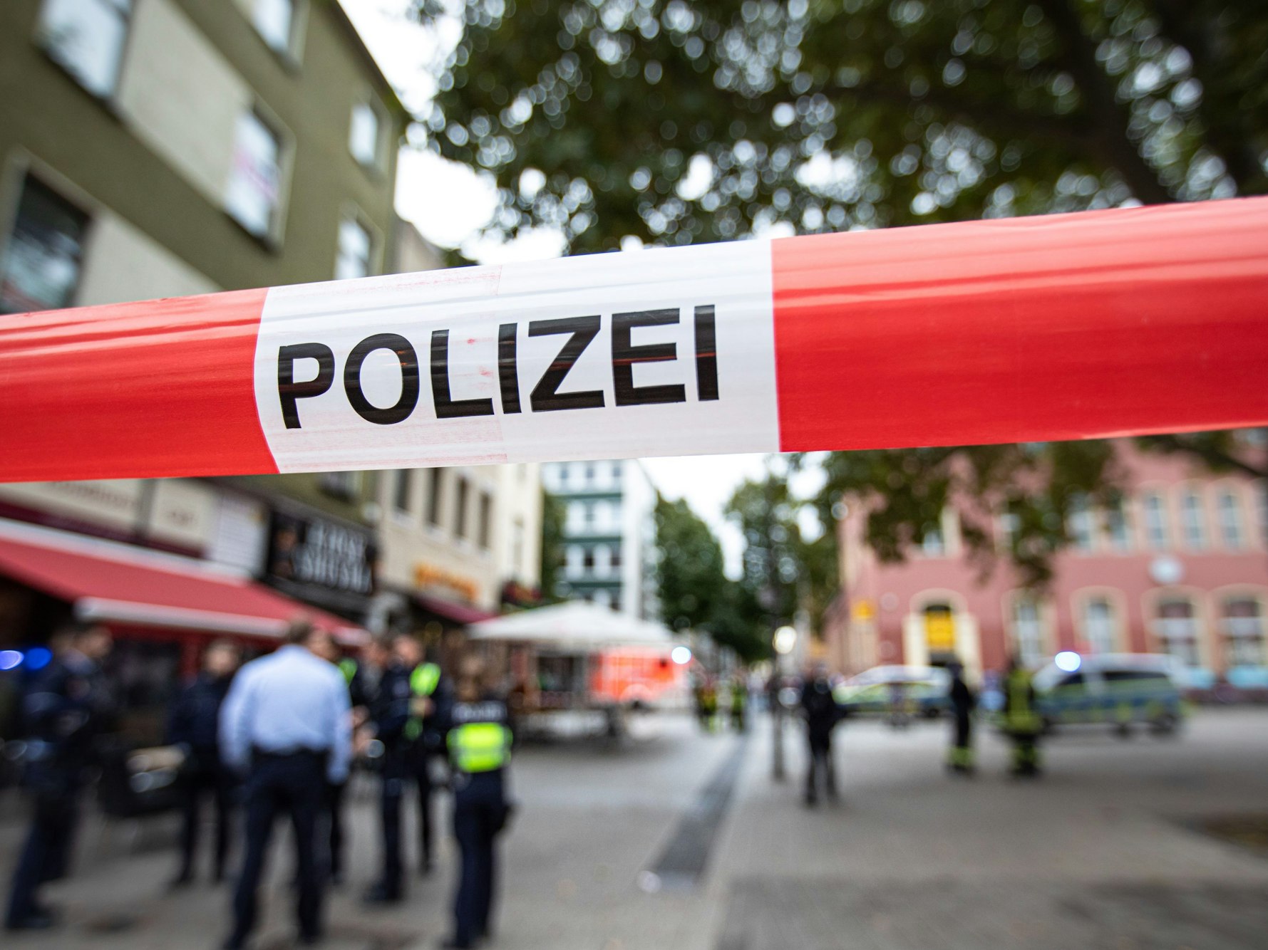 Polizeibeamte und ein Polizeifahrzeug stehen vor einem Geschäft in einer Fußgängerzone.