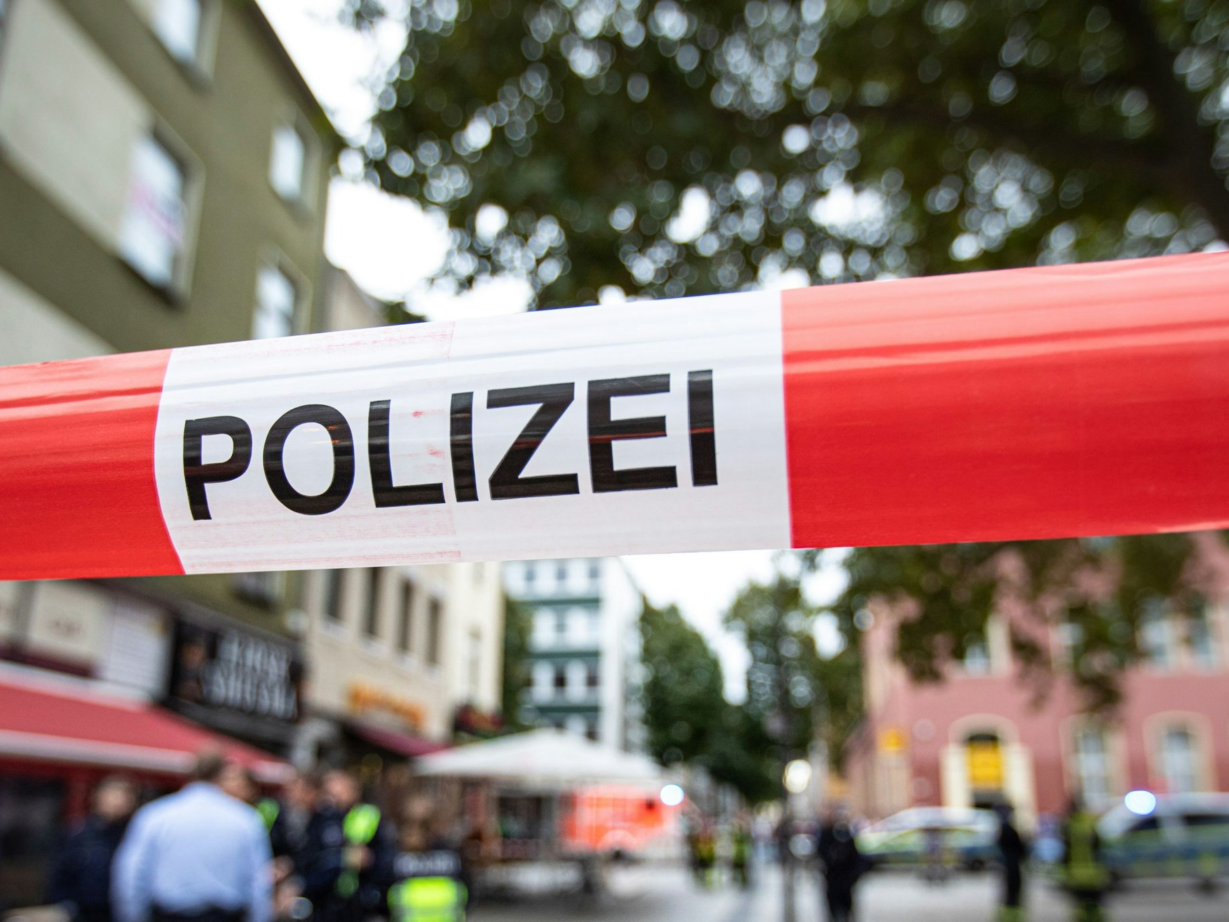 Polizisten und Polizistinnen stehen bei einem Polizeieinsatz vor einem Fast-Food-Laden.