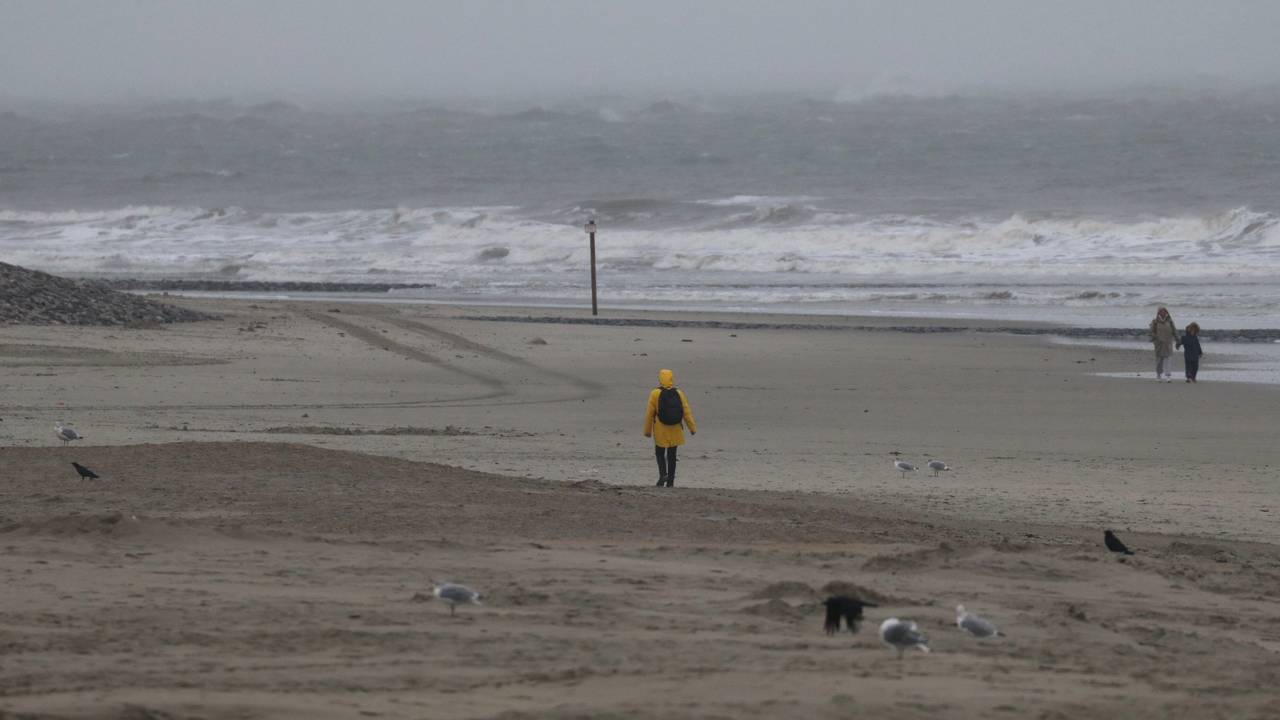 Eine Spaziergängerin geht bei stürmischem Wetter am Strand spazieren.