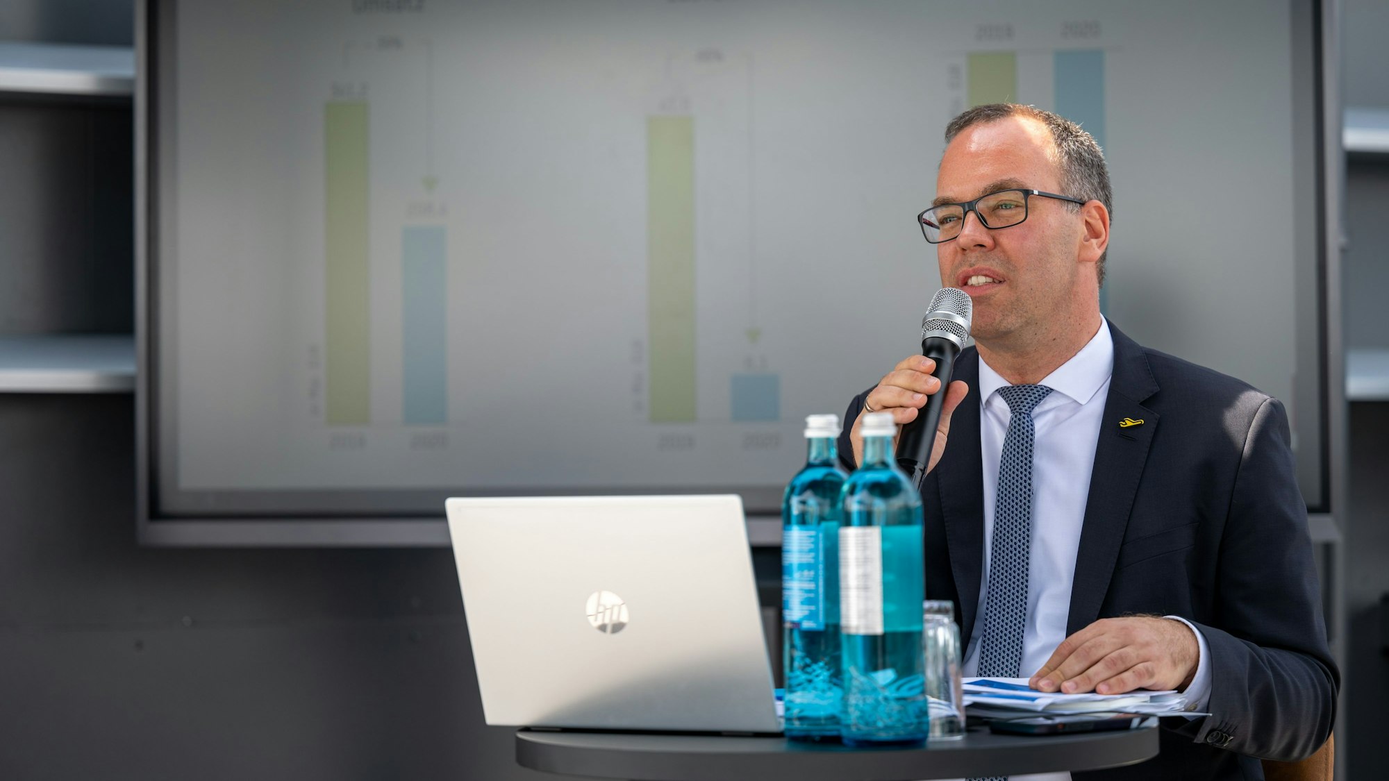 Torsten Schrank sitzt an seinem Laptop und hält mit Mikrofon eine Rede.